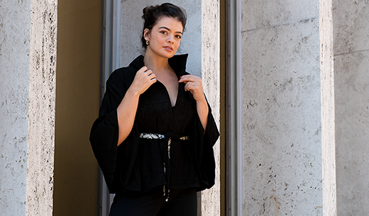 Woman layering Maneesha Ruia's black jacket with ivory embroidered belt over basics