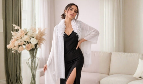 Woman wearing a black dress with a white scarf in a well-lit room.