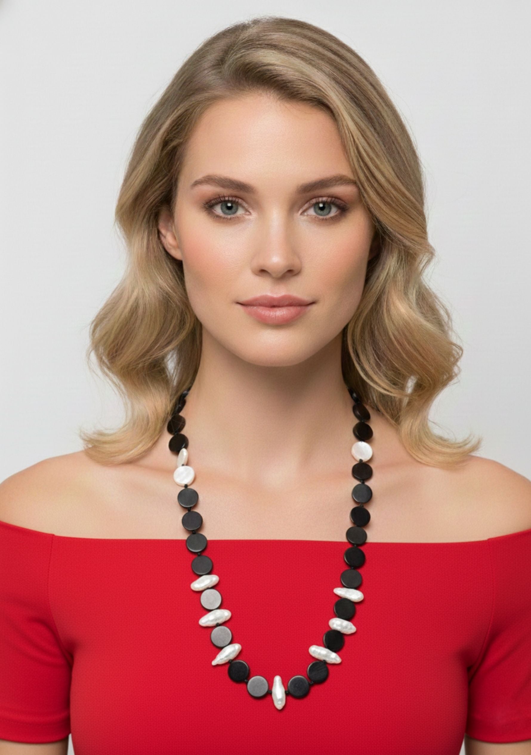 Woman wearing Black Buffalo Horn Disk, White Shell Disk & White Baroque Pearl Necklace beads against a plain background