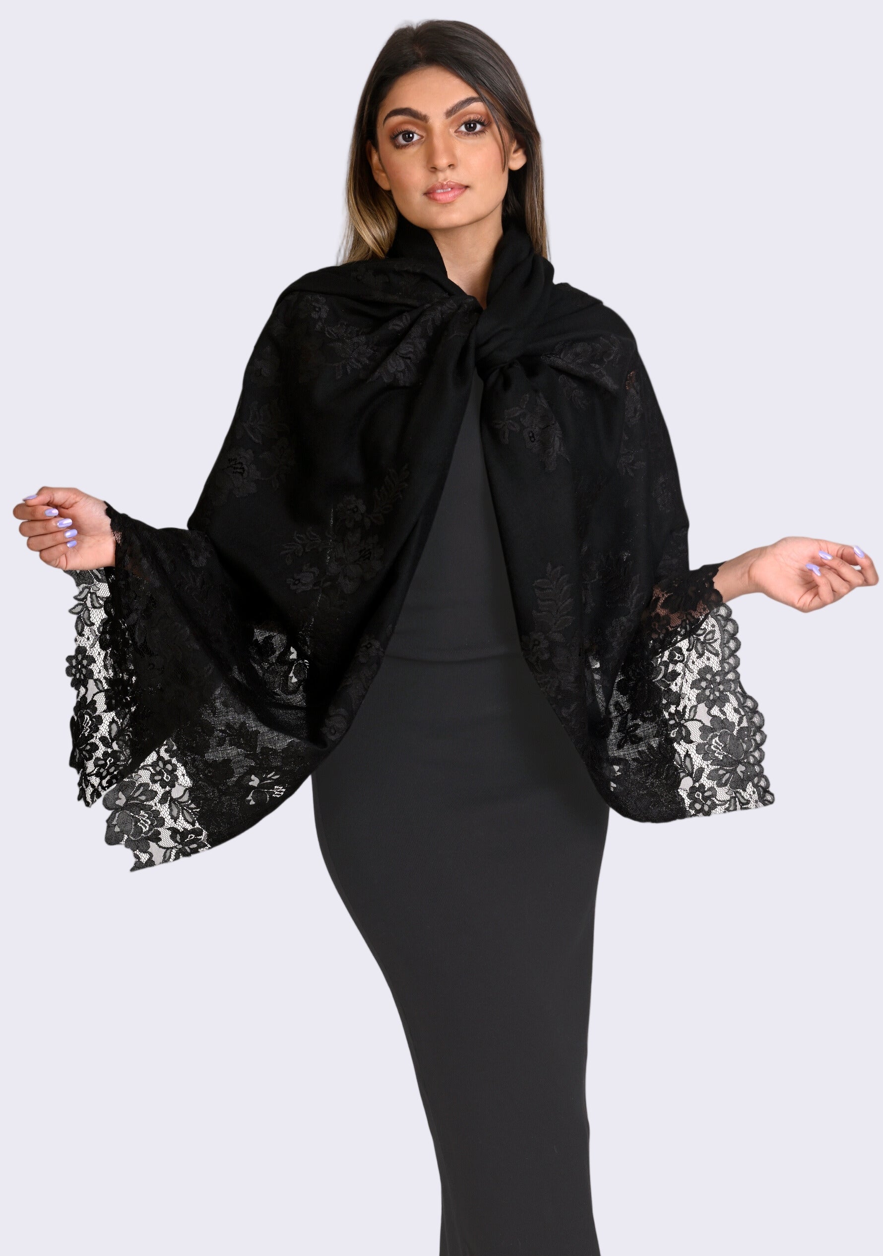 A woman wearing a black cashmere scarf with black Chantilly lace at the ends, tied around the neck.