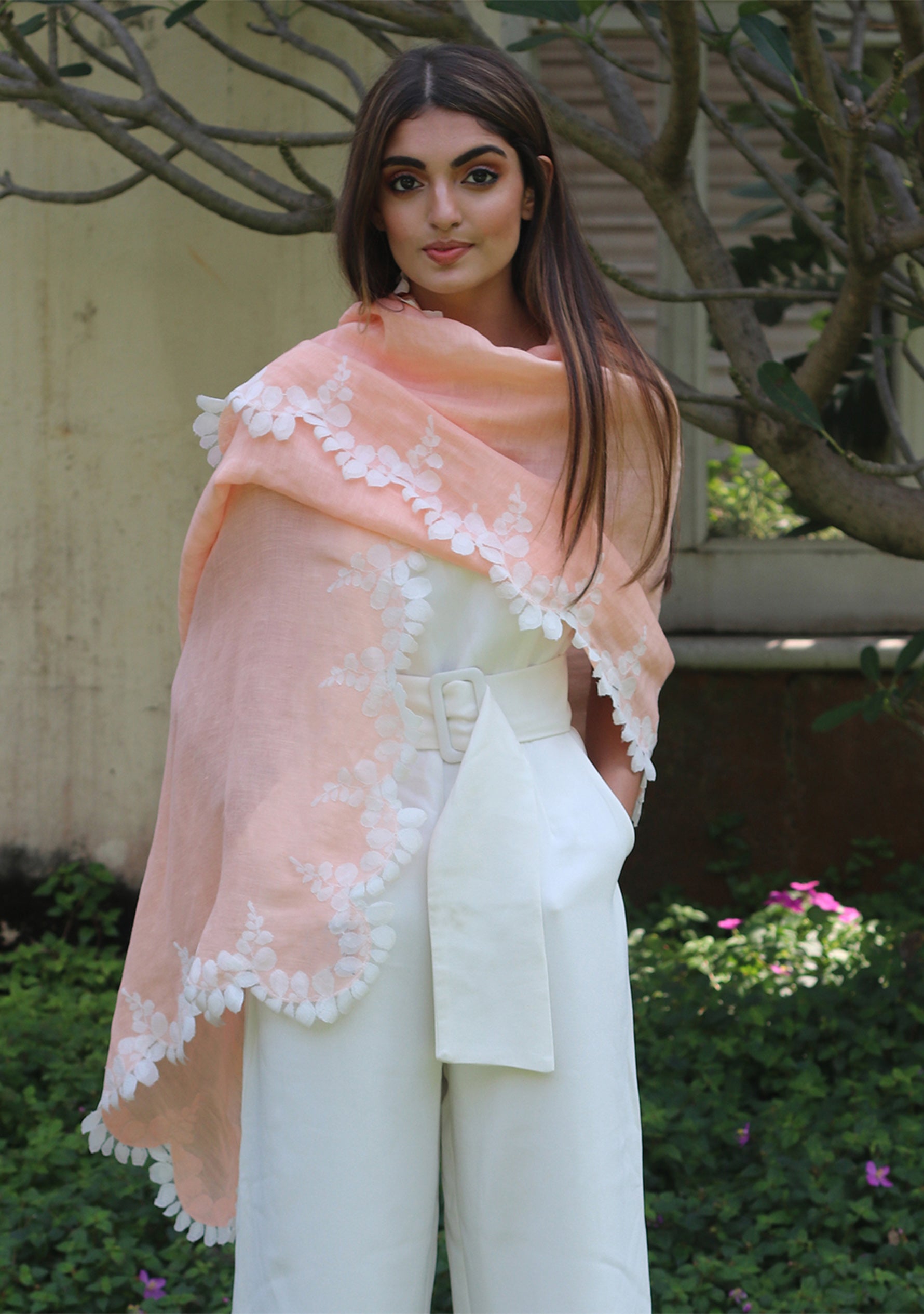 Woman wearing a peach-colored scarf with white-Ivory lace details outdoors.