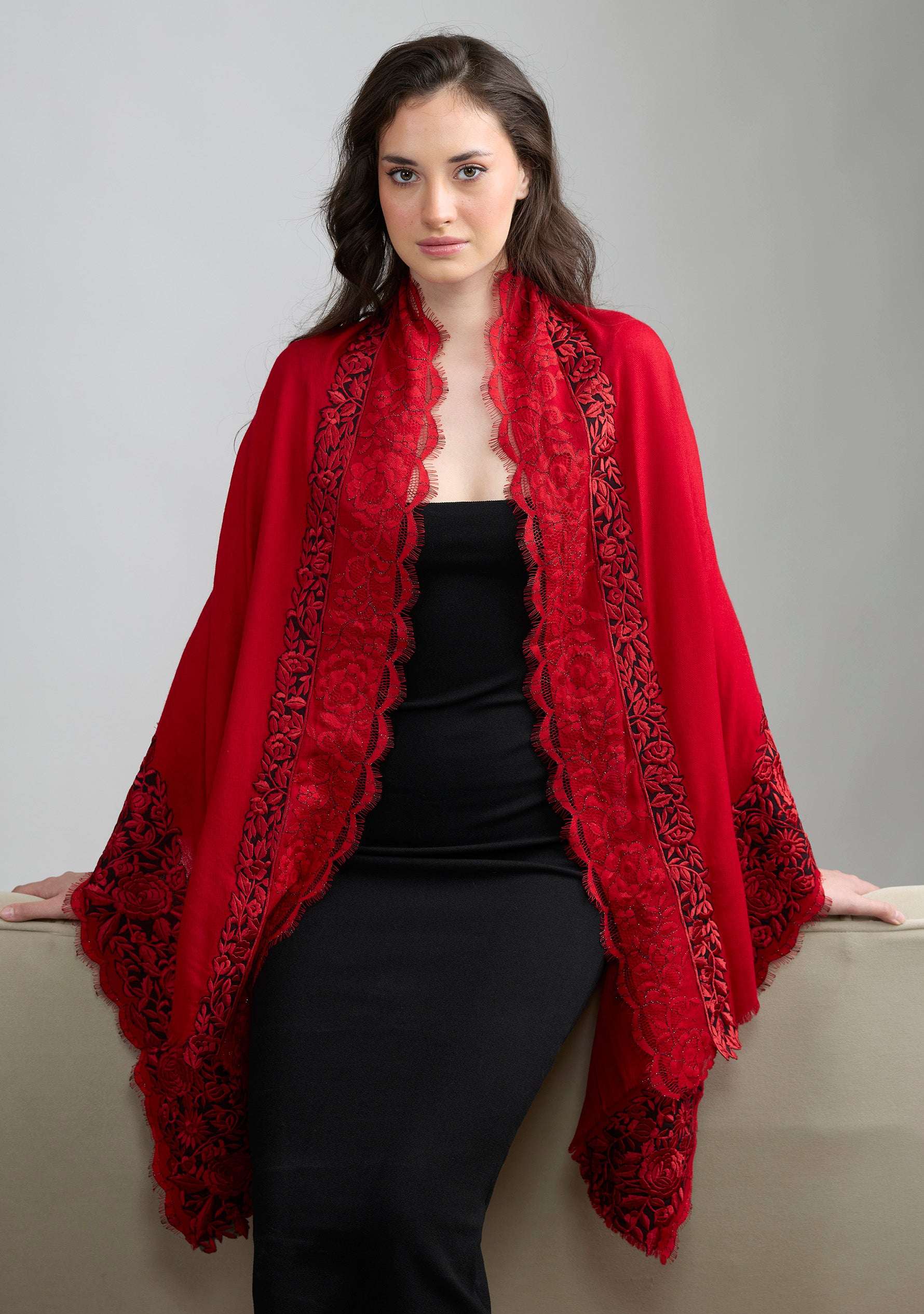 Woman wearing a red shawl with intricate patterns on a gray background