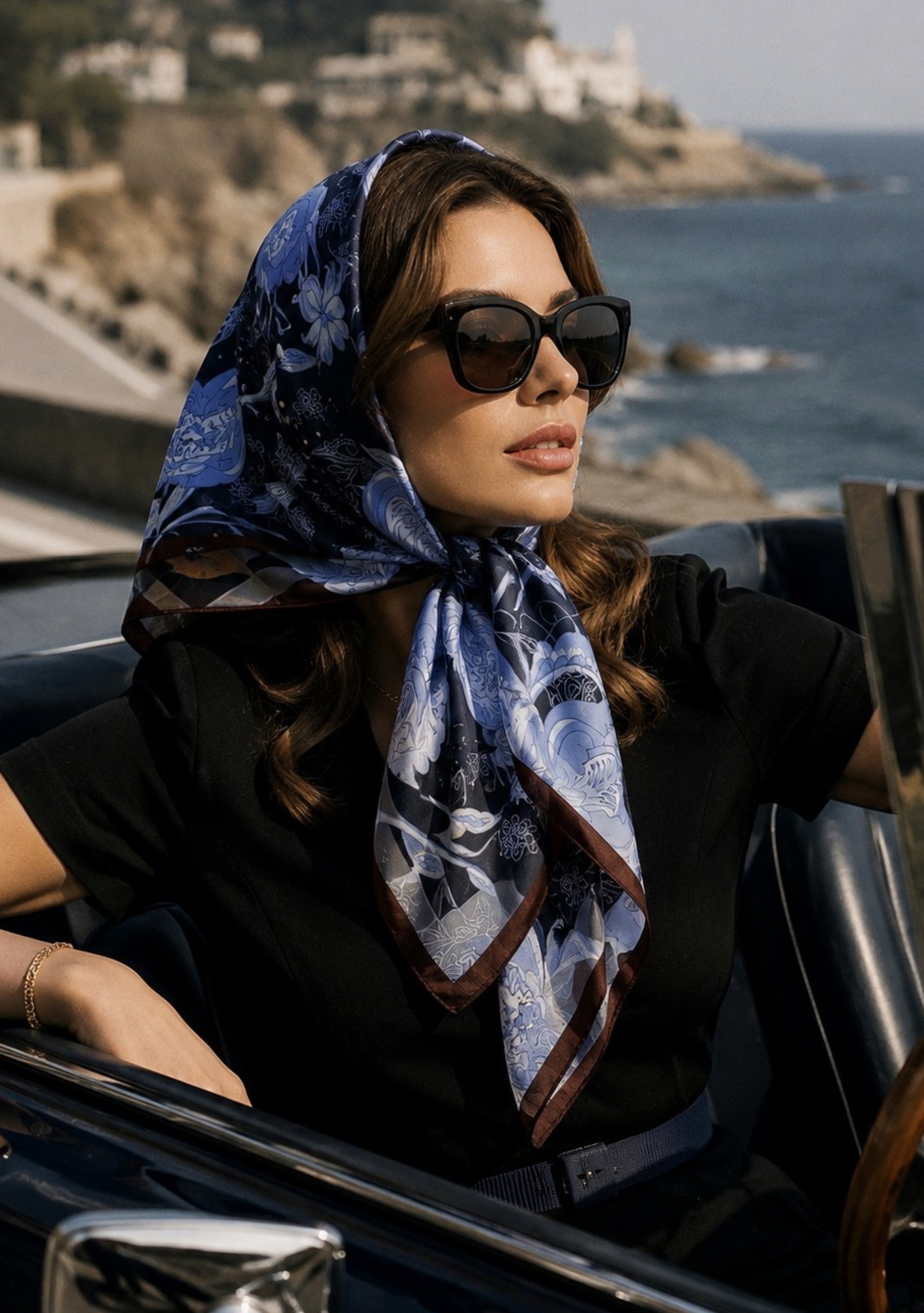 Maneesha Ruia Blue & Brown Jacobean Print Silk Twill Square Scarf with Silver & Gunmetal Swarovski Crystals styled as an elegant silk headscarf with a classic black outfit and luxury coastal look.