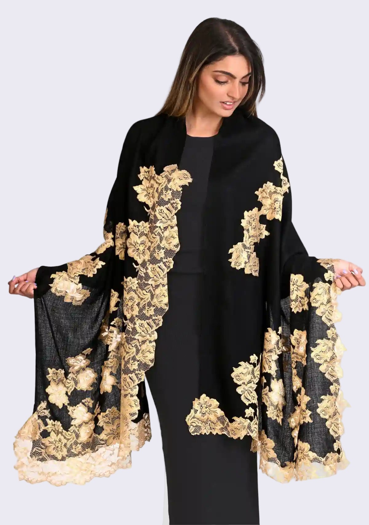 Woman wearing a black outfit with gold floral embroidery on a white background