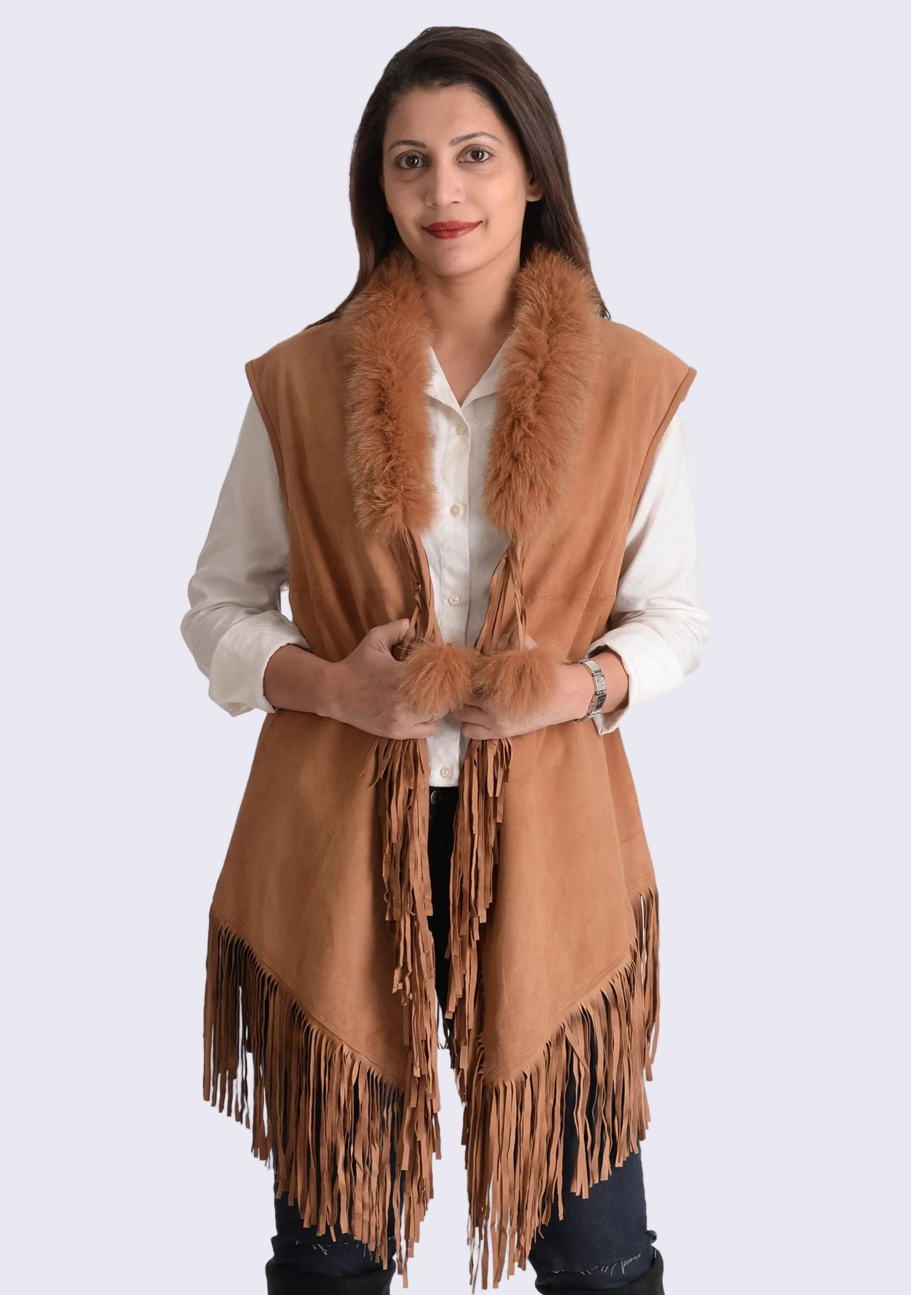 A woman wearing a tan suede leather sleeveless jacket with long tassels and fur collar.