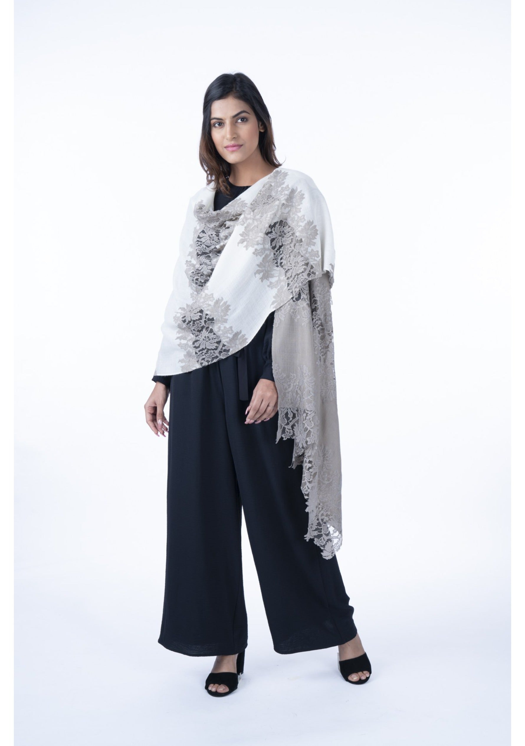 A woman wearing a black outfit and a dual-colored cashmere scarf with natural hibiscus lace panels.