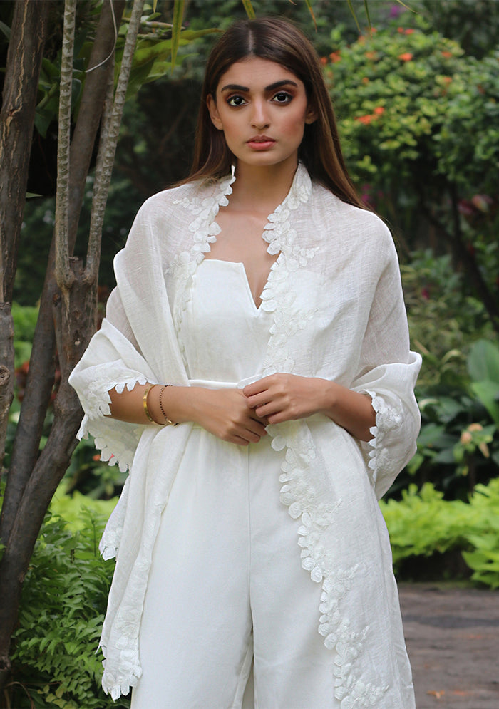 Woman wearing a white outfit with floral details in a garden setting