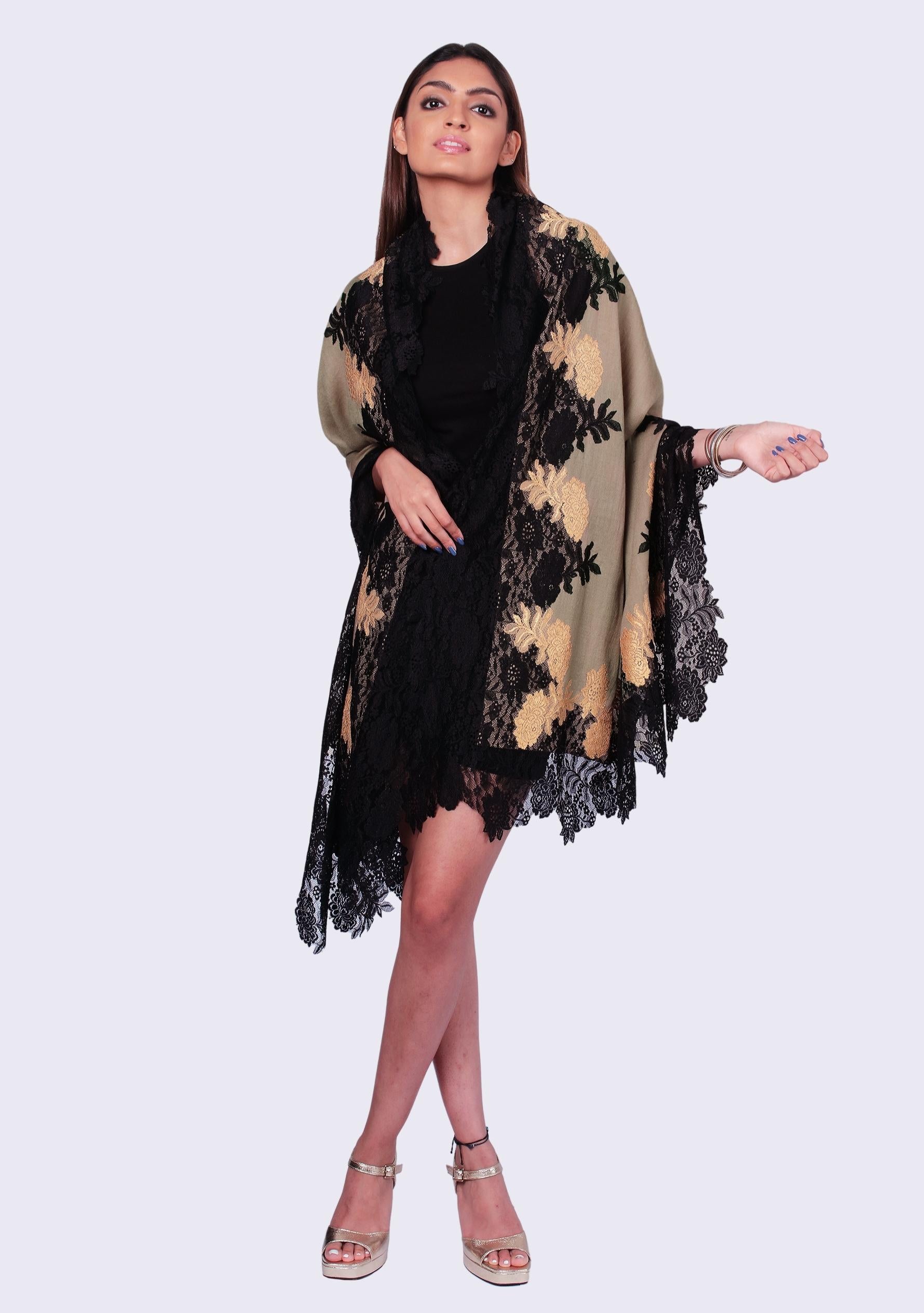 Woman wearing a black dress with a beige and black floral patterned shawl on a white background