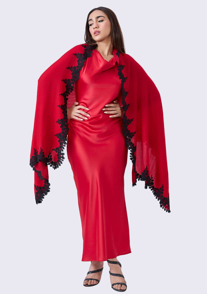 Woman wearing a red dress with black lace details on a white background