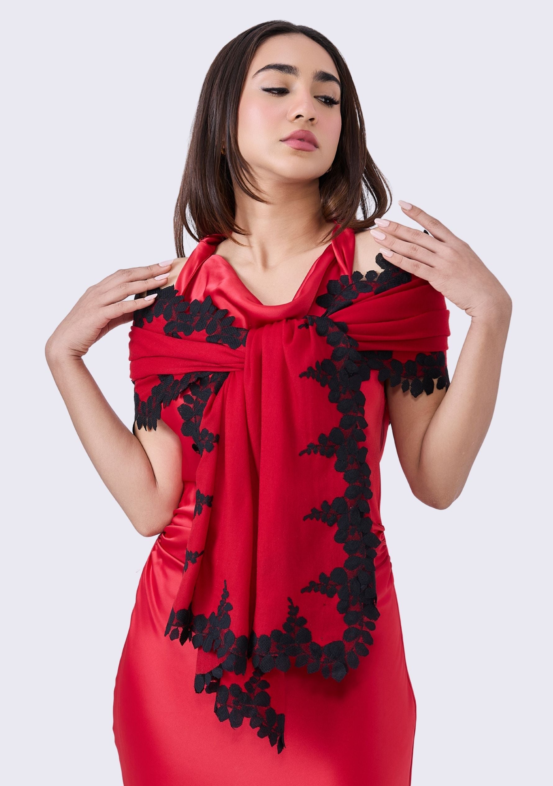 Woman wearing a red dress with black lace details on a white background
