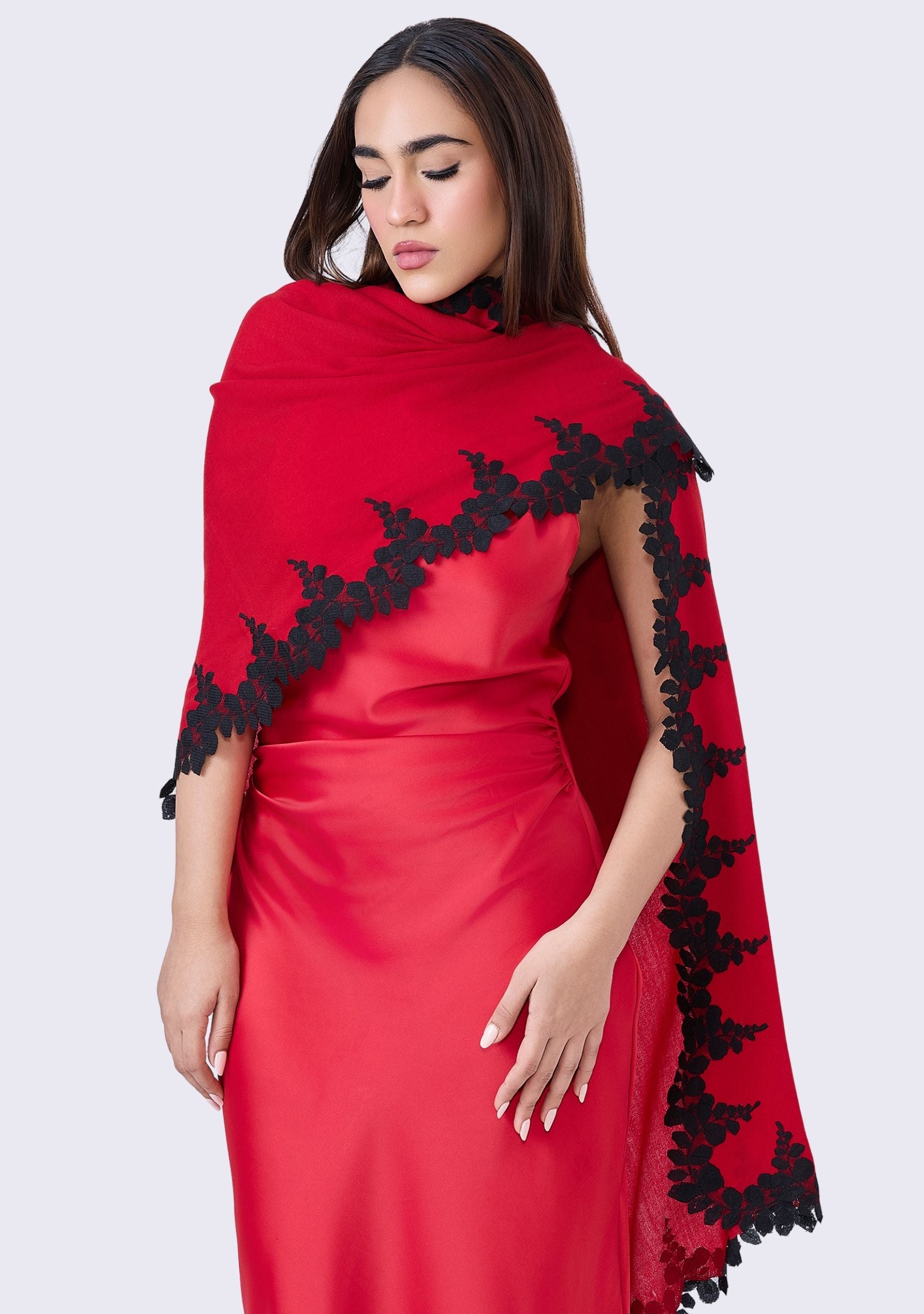 Woman wearing a red dress with black lace details on a white background