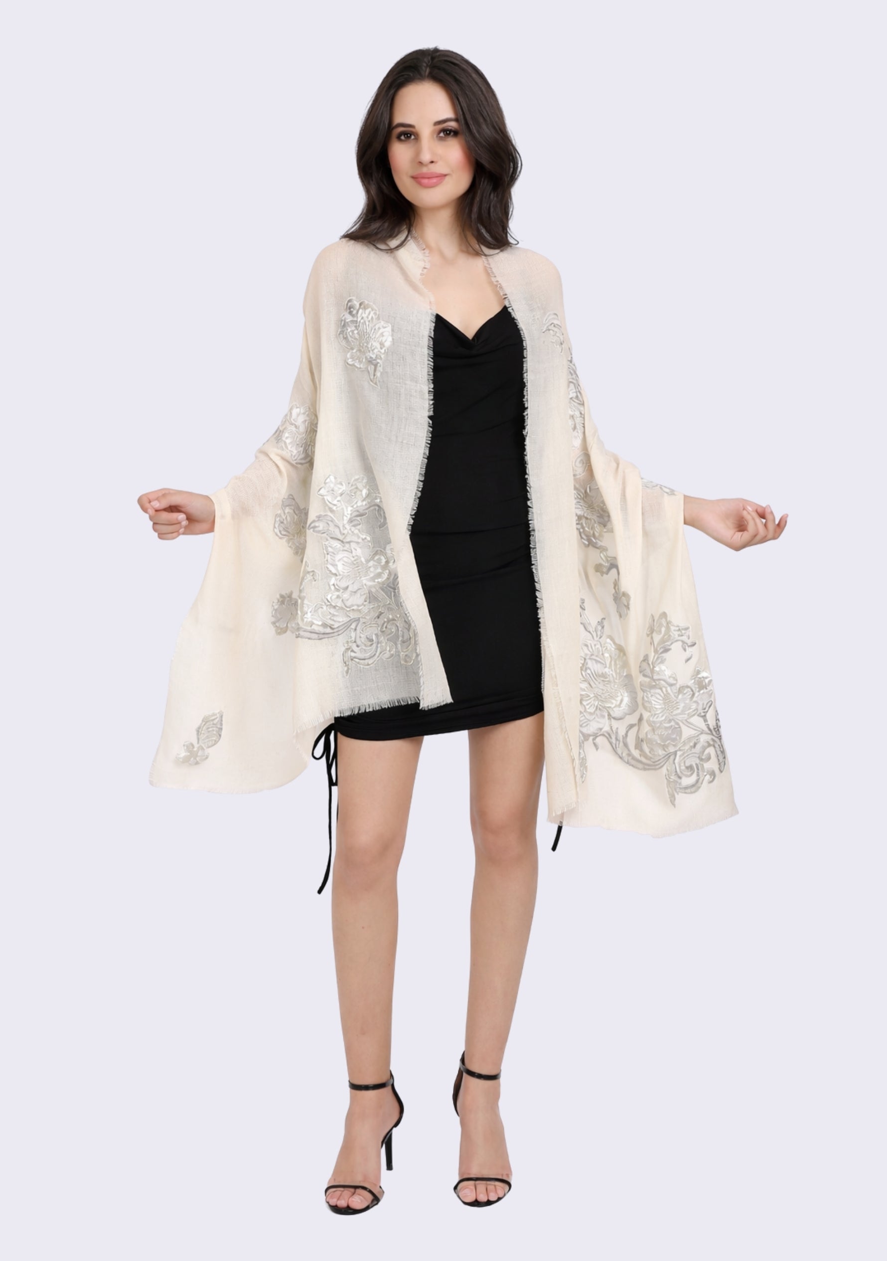Woman wearing a Maneesha Ruia ivory cashmere shawl over a black top against a neutral background