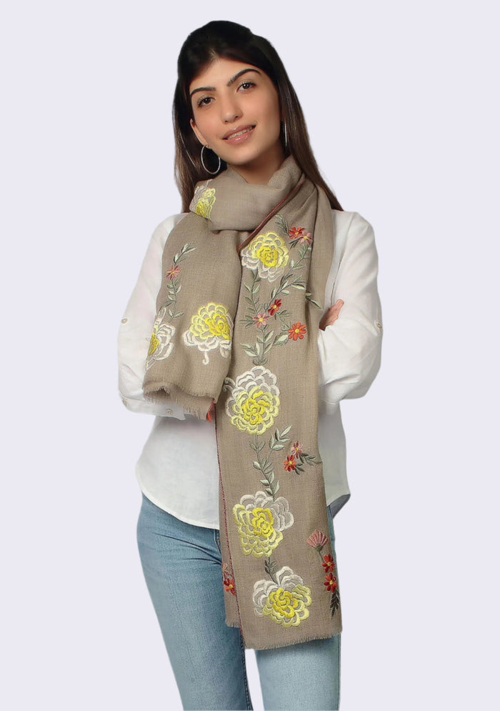 Woman wearing a beige scarf with floral embroidery on a white background