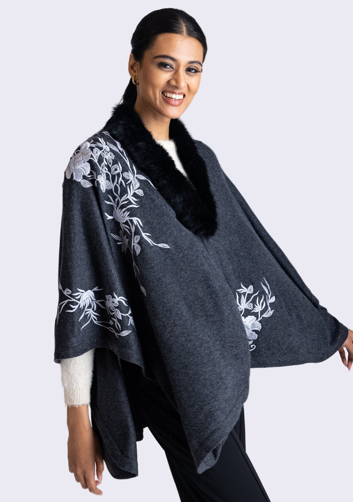 A model wearing a charcoal melange wool cape with light gray embroidery and a black faux fur collar.