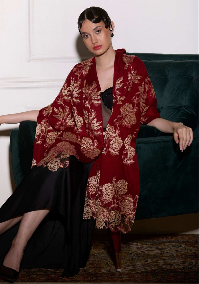 Woman wearing a red floral kimono-style garment sitting on a green couch.