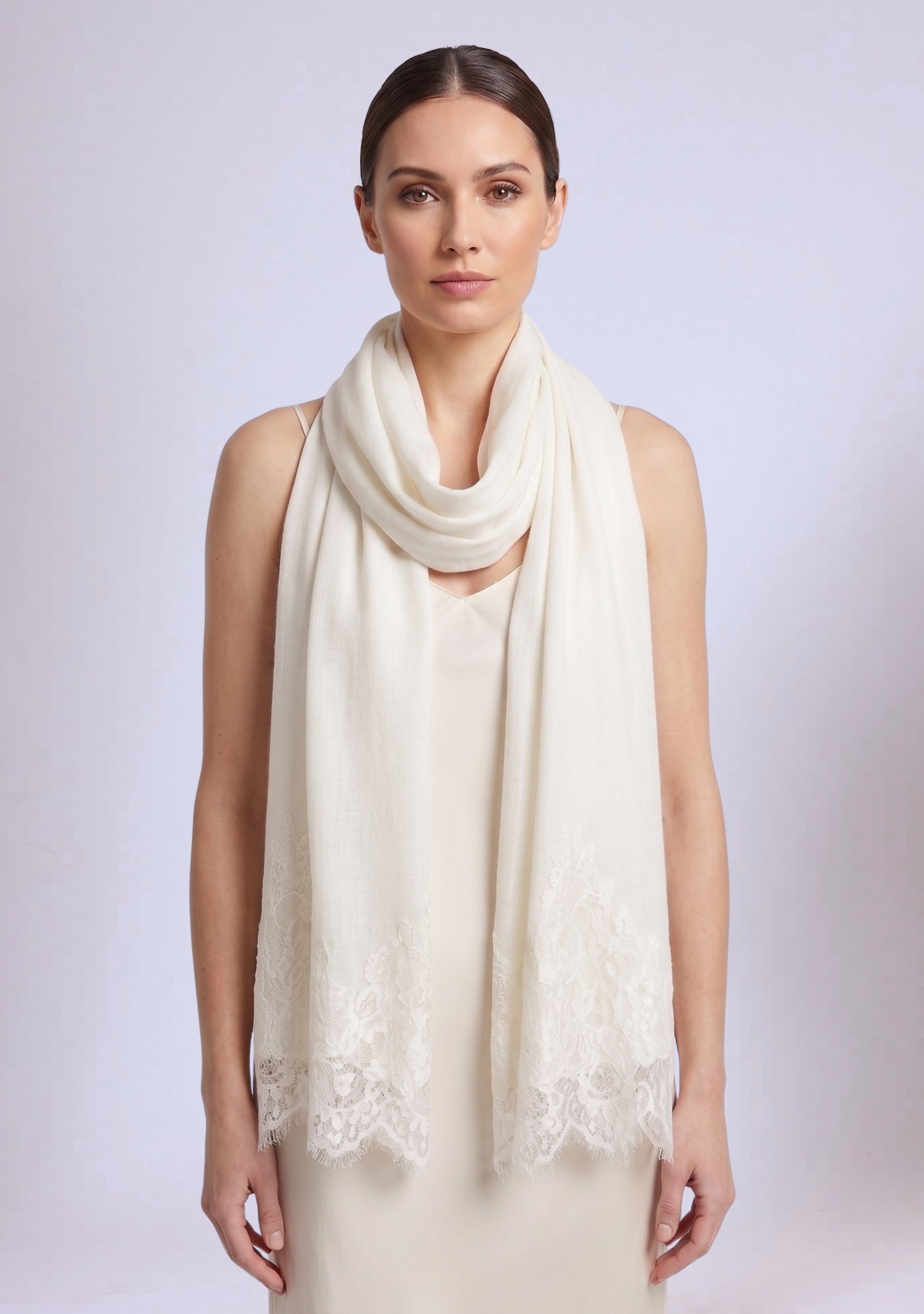Woman wearing a ivory scarf and dress against a plain background