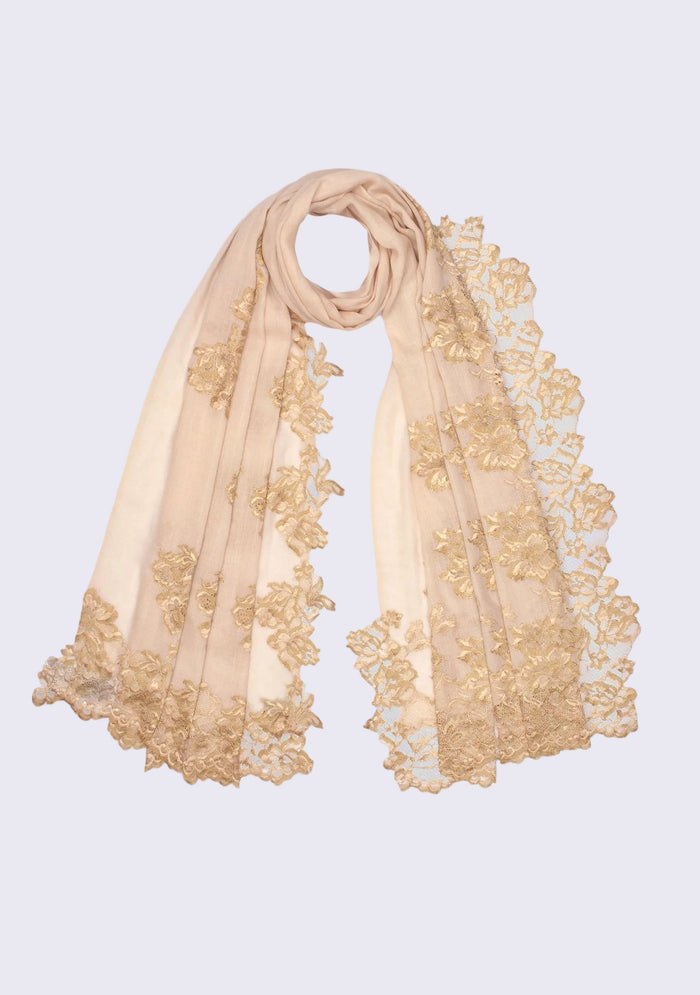 Luxury beige cashmere scarf featuring intricate gold Chantilly floral lace appliqué and delicate handcrafted detailing on a light grey background.