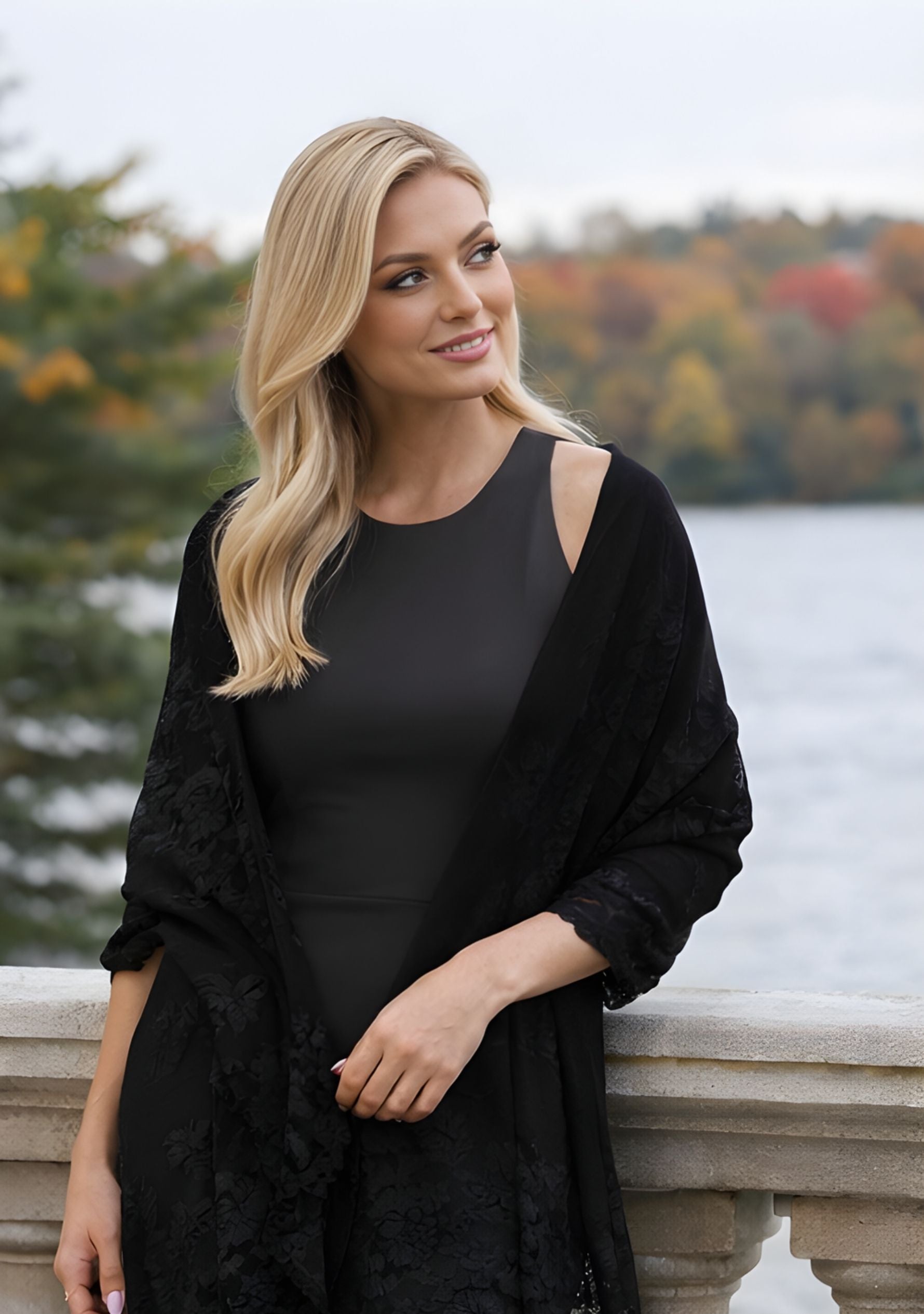 Elegant woman wearing a luxury black cashmere scarf with handcrafted black Chantilly lace while strolling outdoors, showcasing timeless sophistication for evening events, travel, and elevated everyday style.