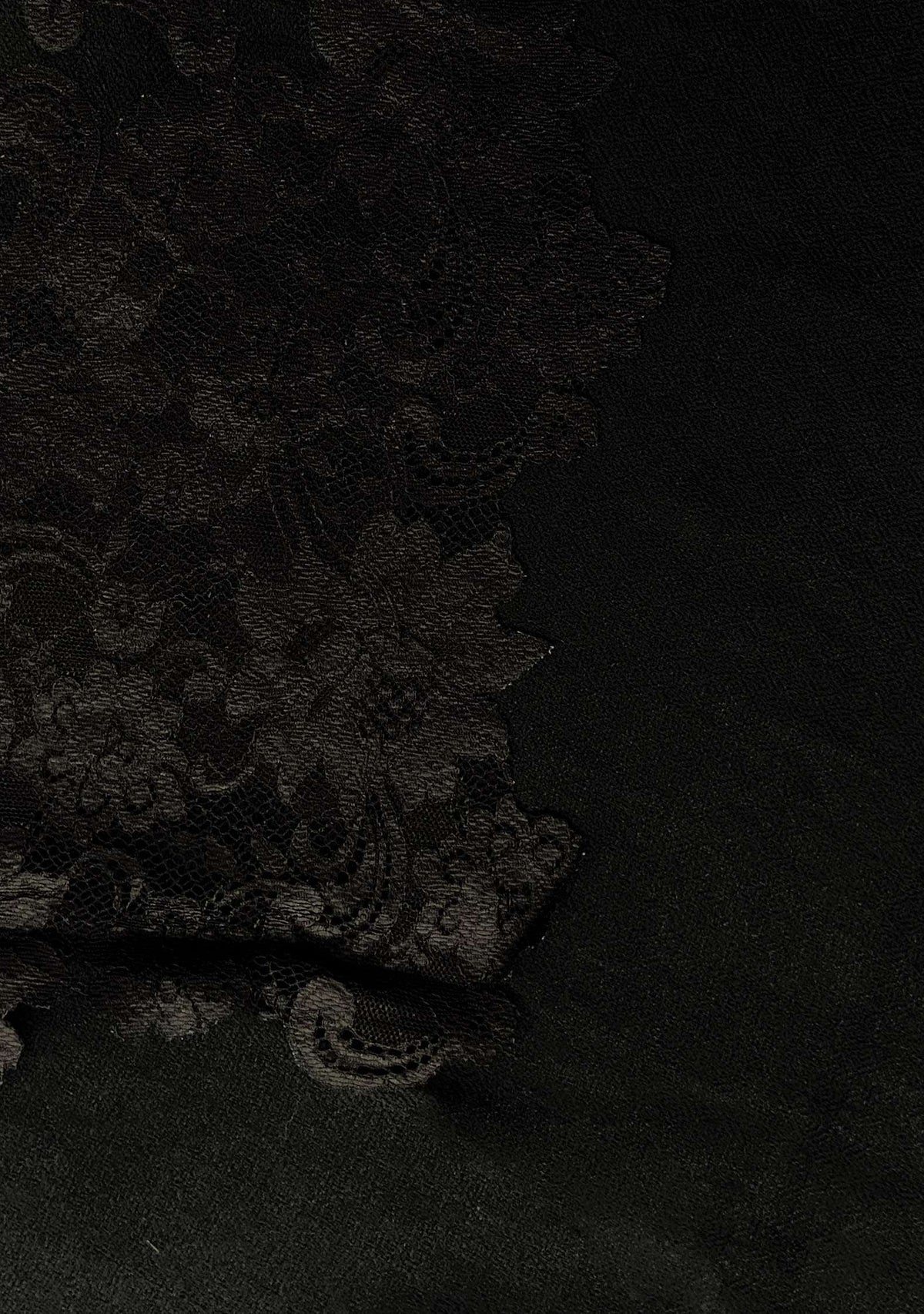 Close-up of black Chantilly floral lace appliqué on a black cashmere scarf, highlighting intricate craftsmanship and premium detailing.