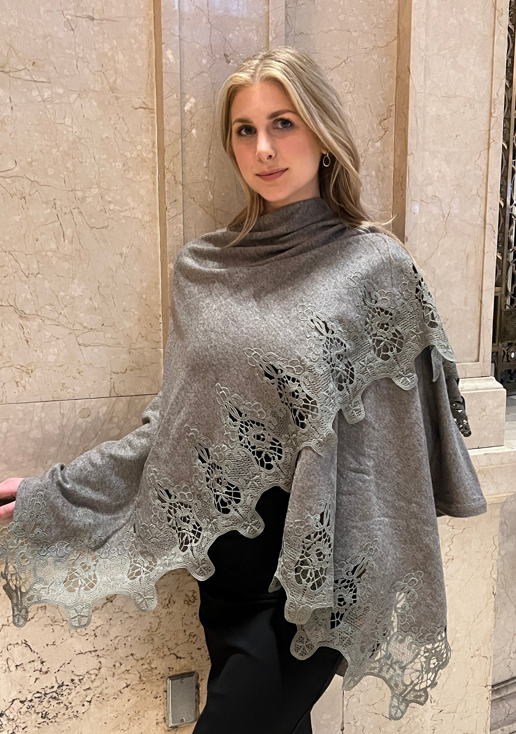 Woman wearing a gray poncho with lace details in an indoor setting