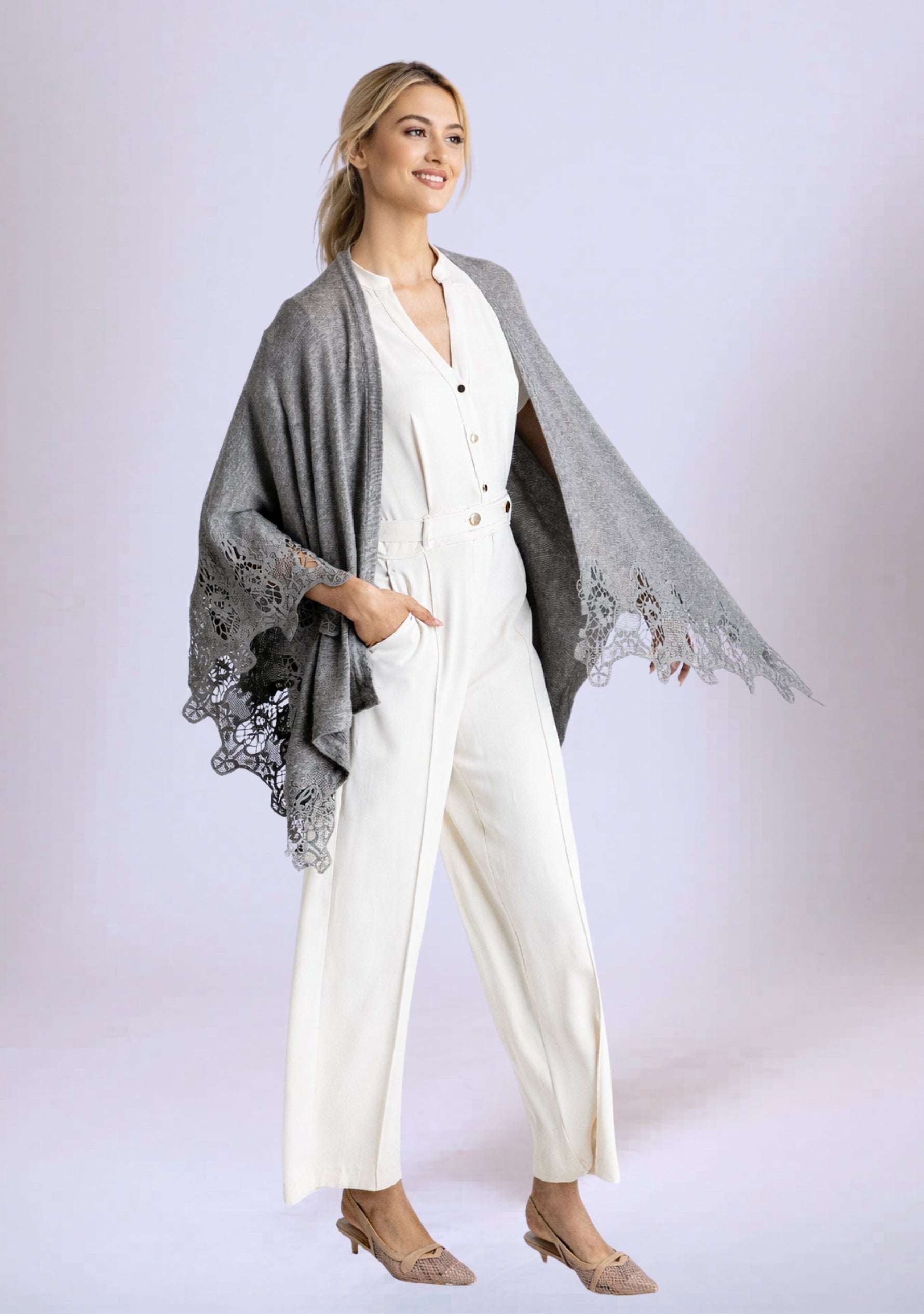 Woman wearing a white outfit with a gray poncho on a light background