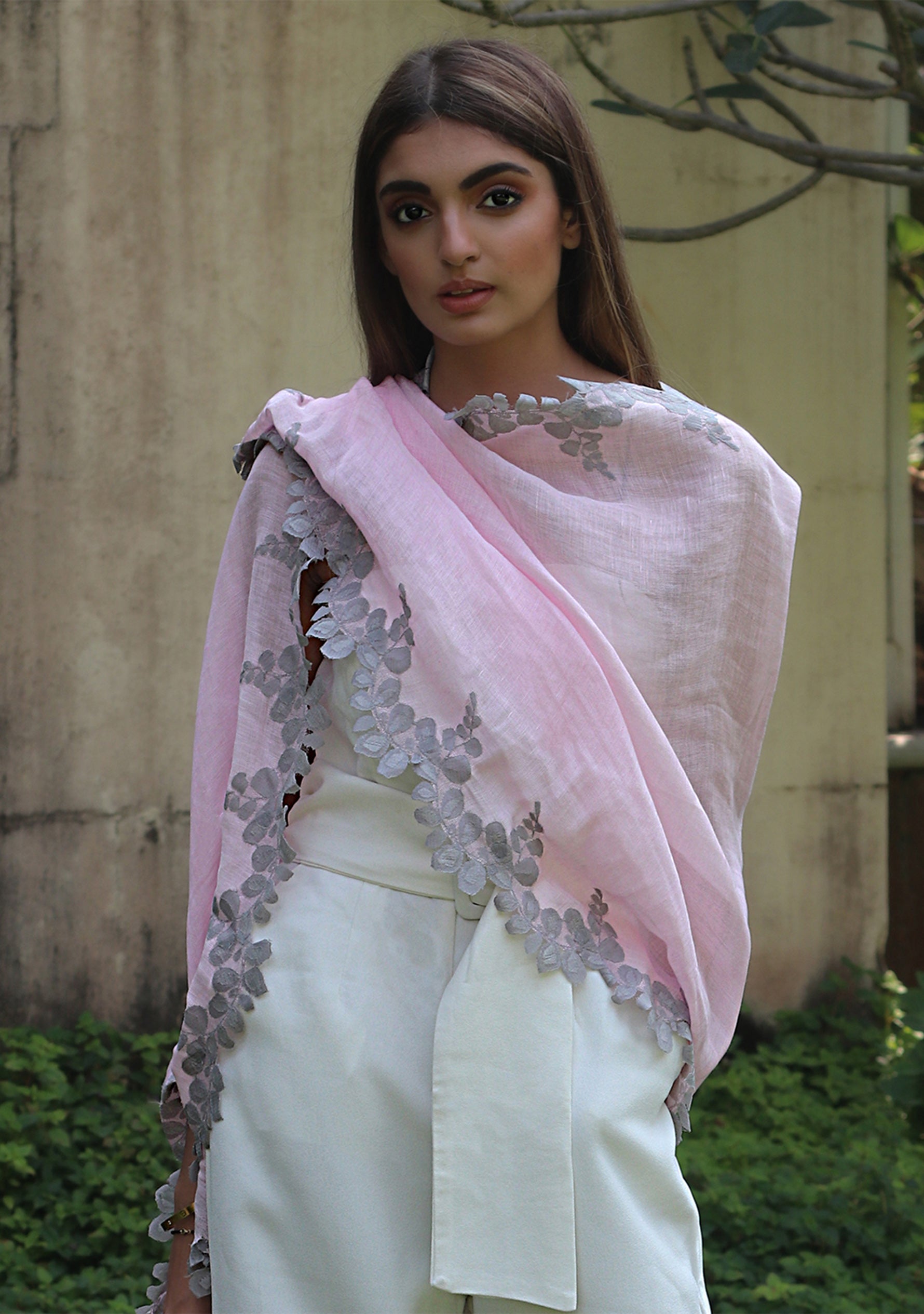 Woman wearing a light pink scarf with floral patterns in an outdoor setting