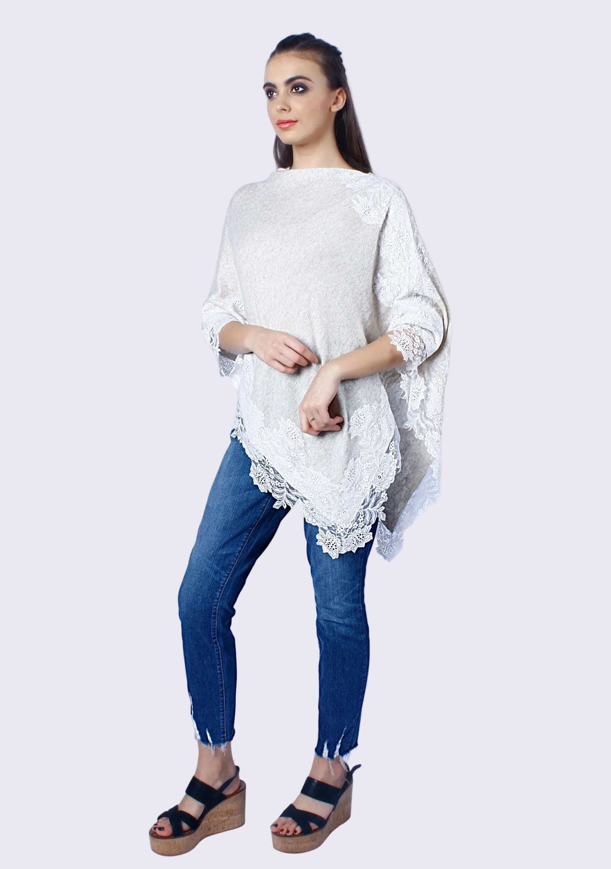 Woman wearing a white lace top and blue jeans on a white background