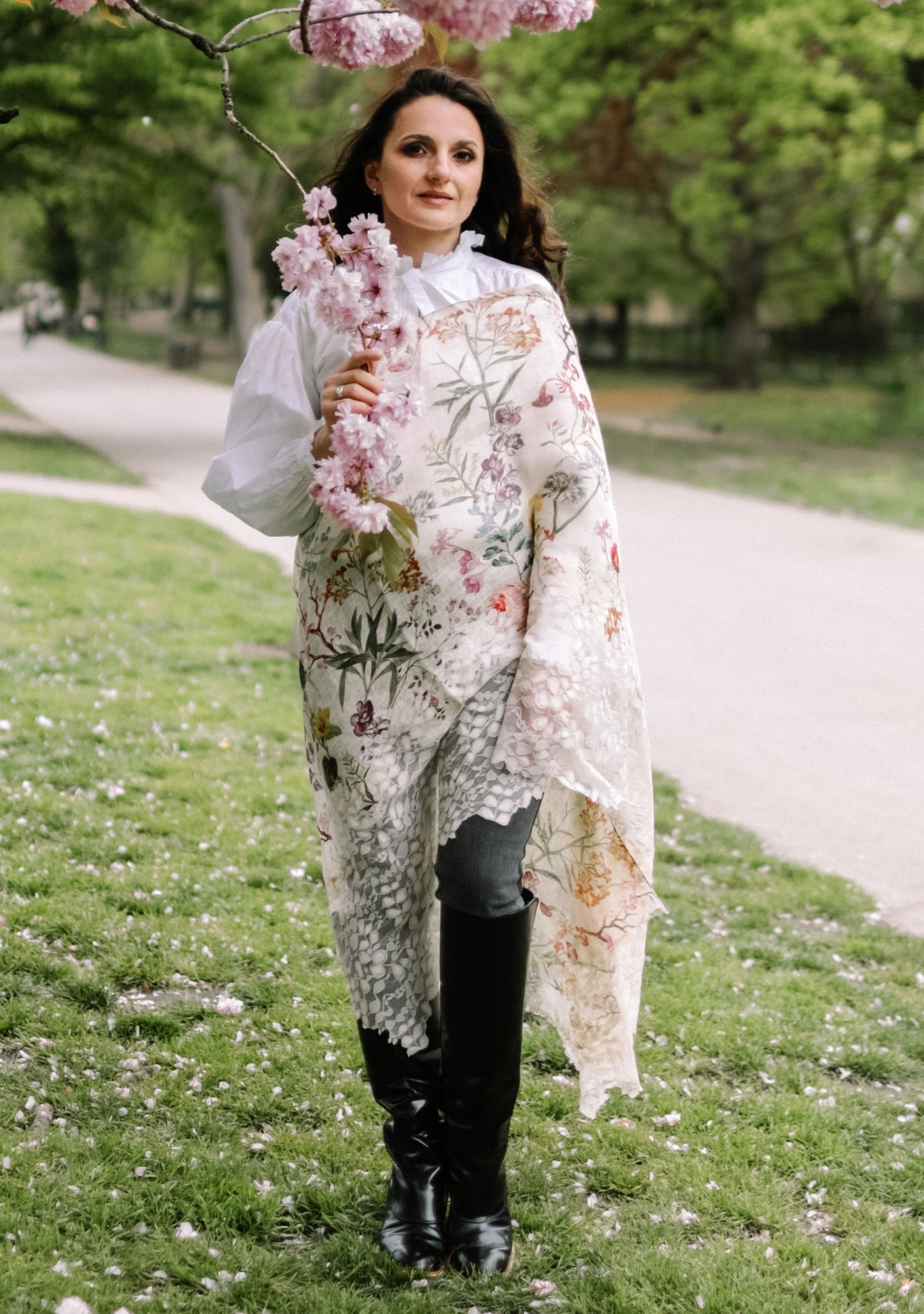 Woman in a floral dress holding cherry blossoms in a park