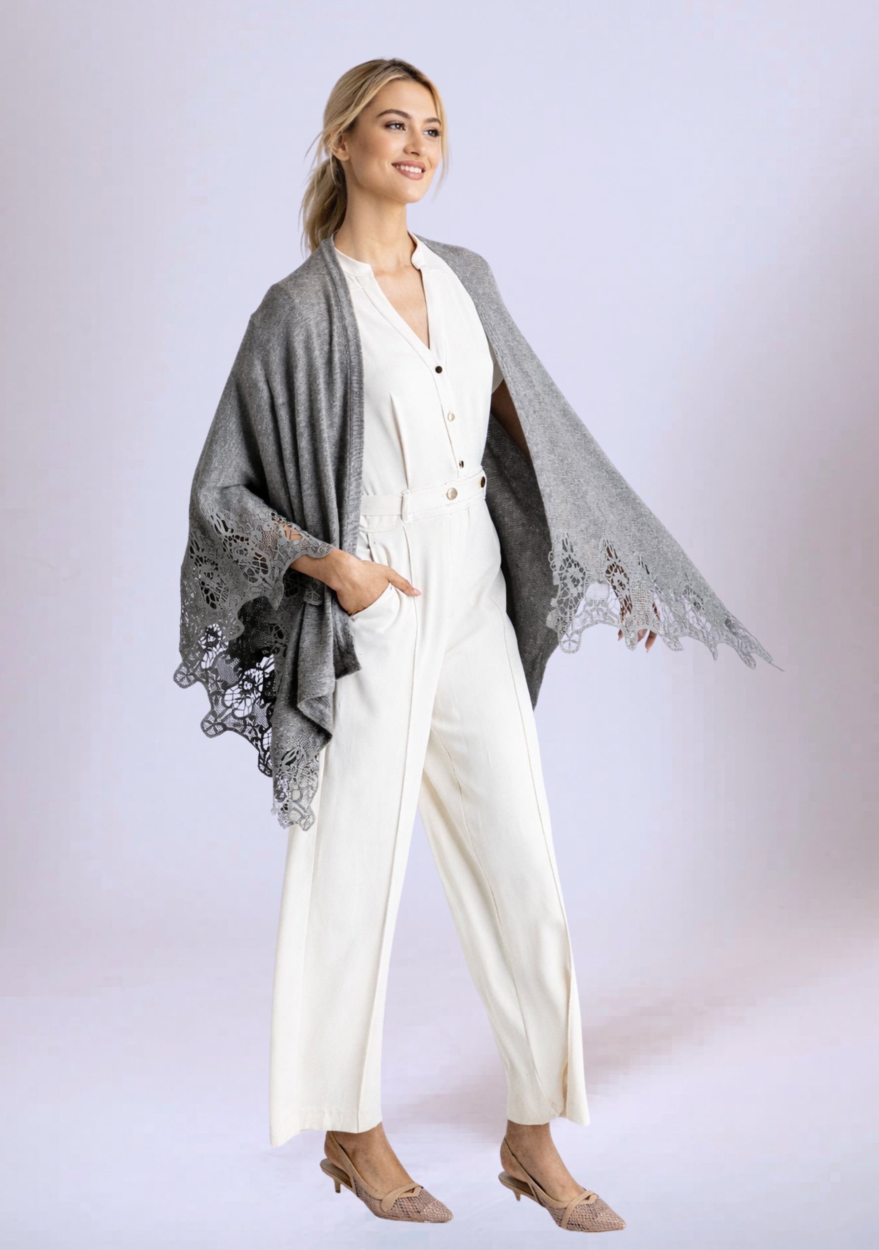 Woman wearing a white outfit with a gray poncho on a light background
