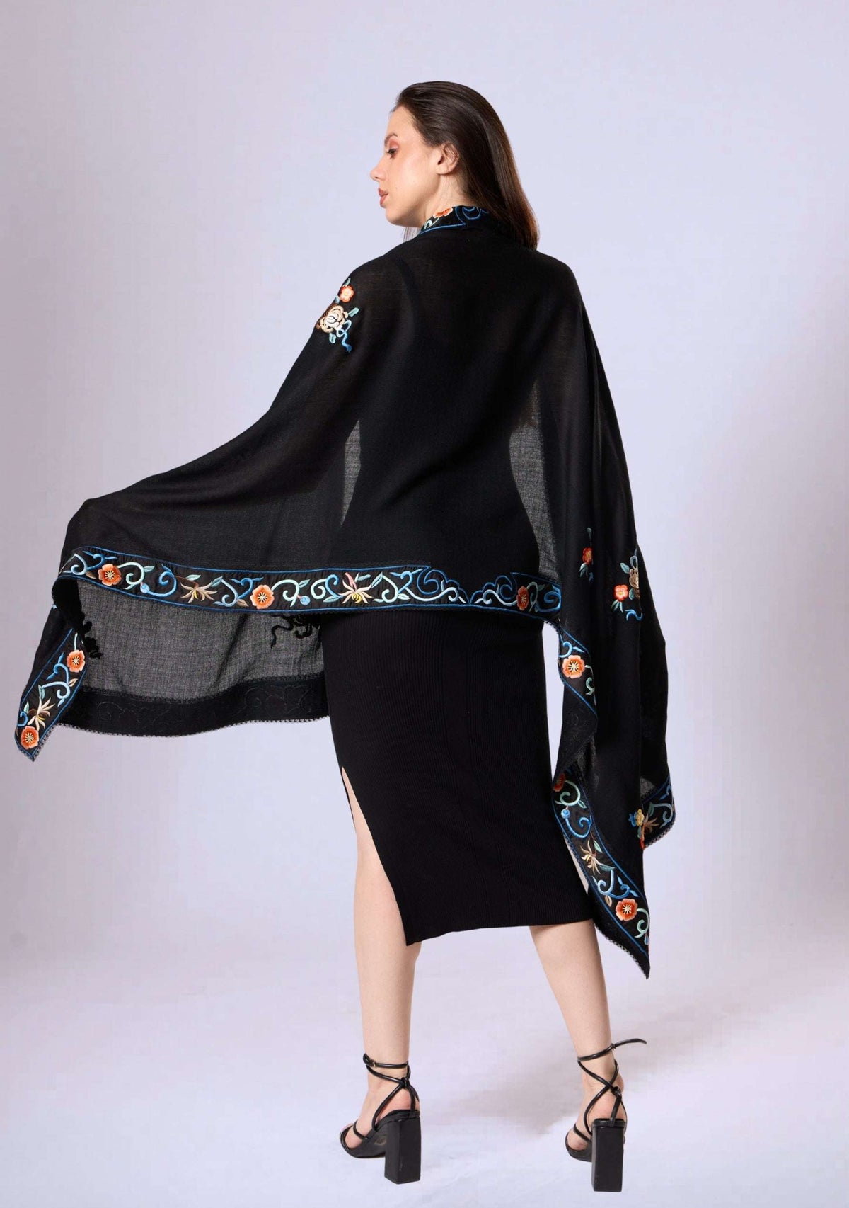 Woman wearing a black shawl with colorful embroidery on a white background