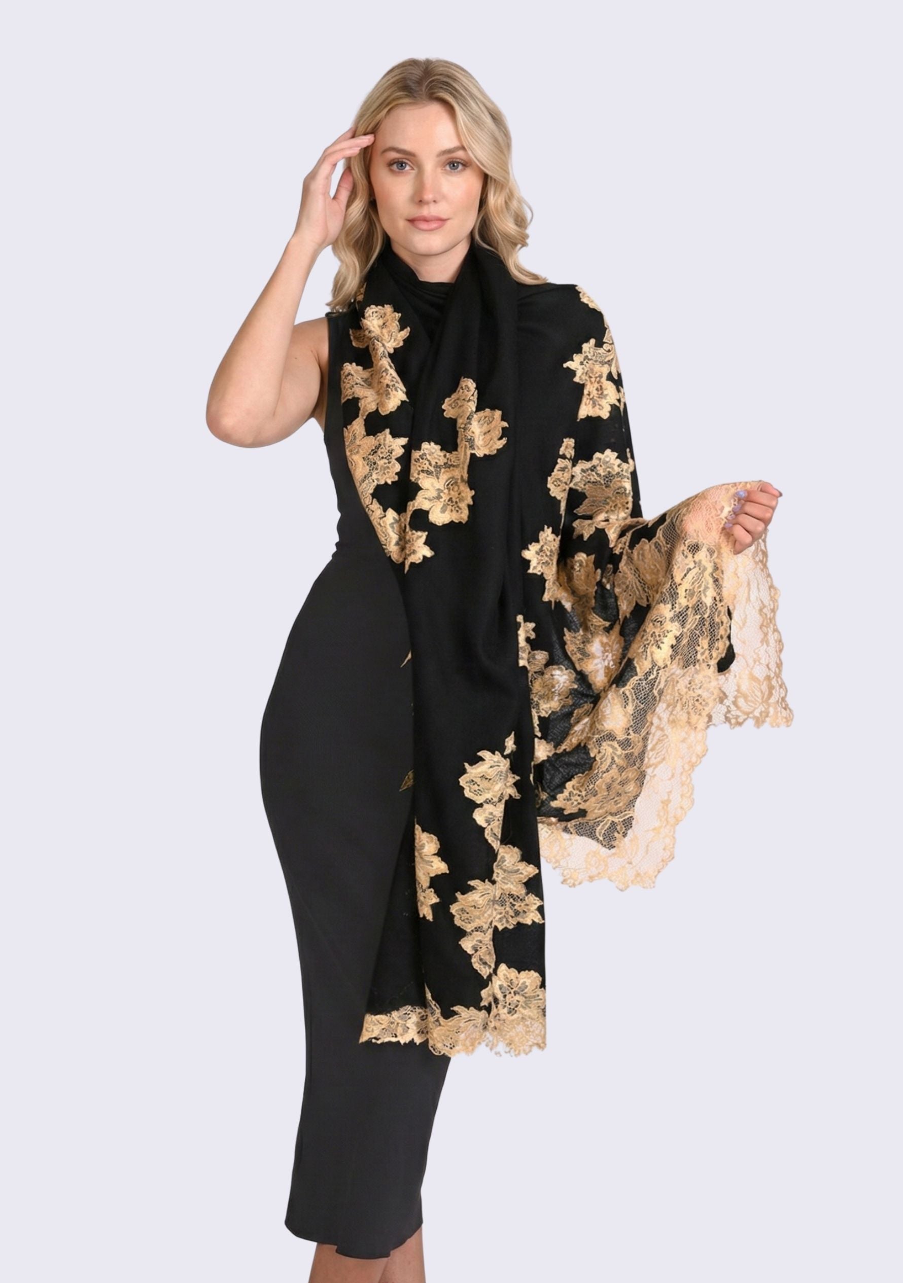 Luxury black cashmere scarf with handcrafted gold Chantilly lace in a floral vine pattern, elegantly draped on a smiling female model wearing a black off-shoulder dress. Soft, lightweight designer scarf with intricate lace detailing, perfect for formal occasions and timeless luxury styling.