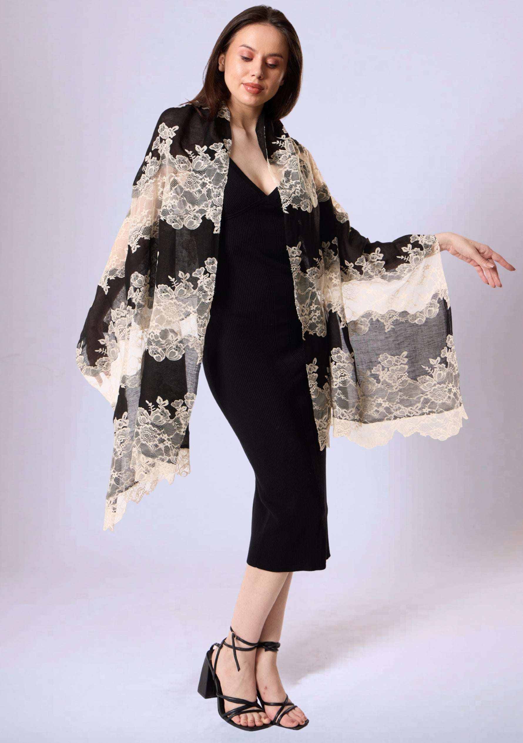 Woman wearing a black dress with a floral lace shawl on a white background