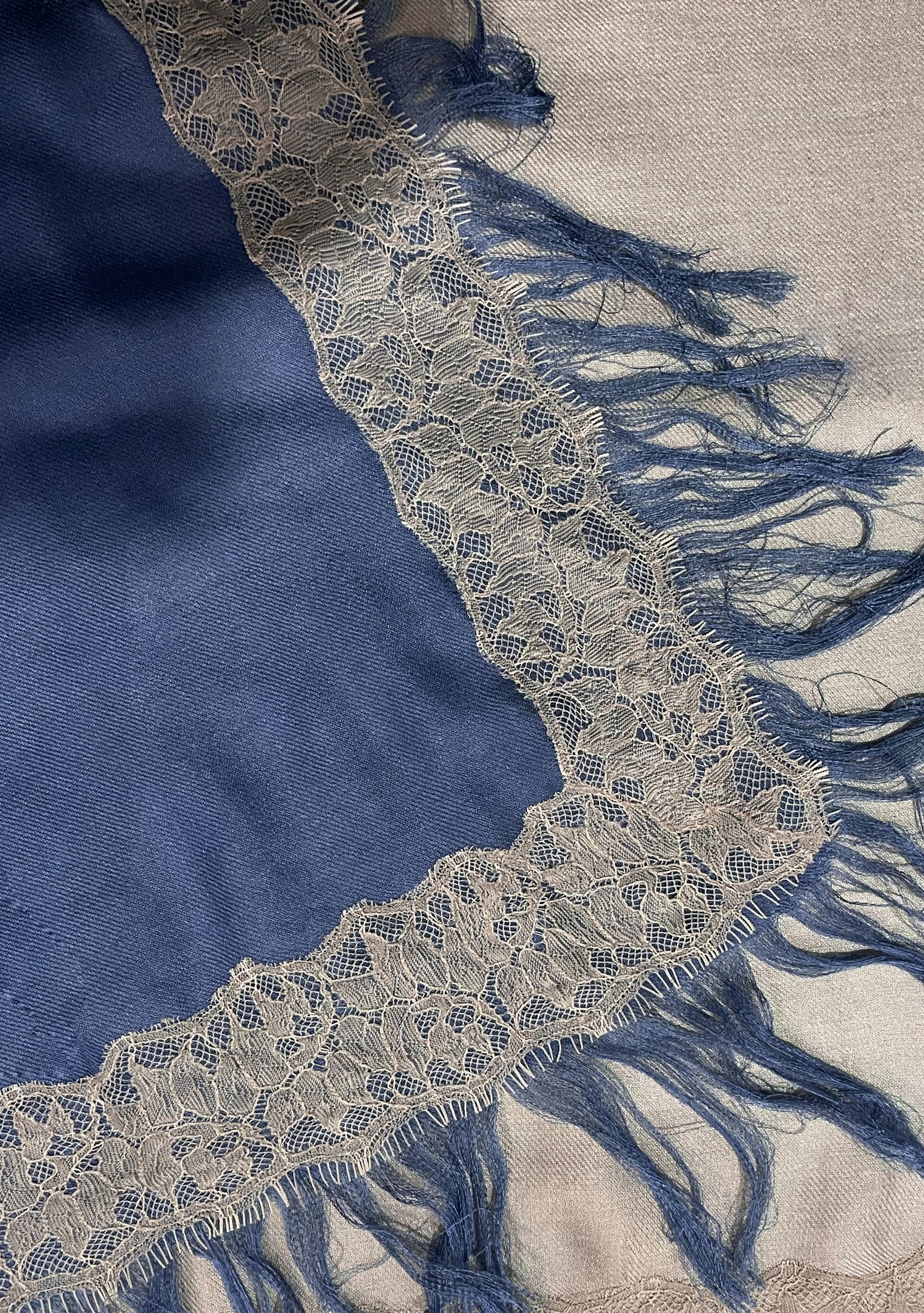 Close-up of the Maneesha Ruia Denim Ombré Modal & Cashmere Scarf featuring beige floral lace trim, a beige-to-denim blue ombré gradient, and soft hand-knotted fringes.