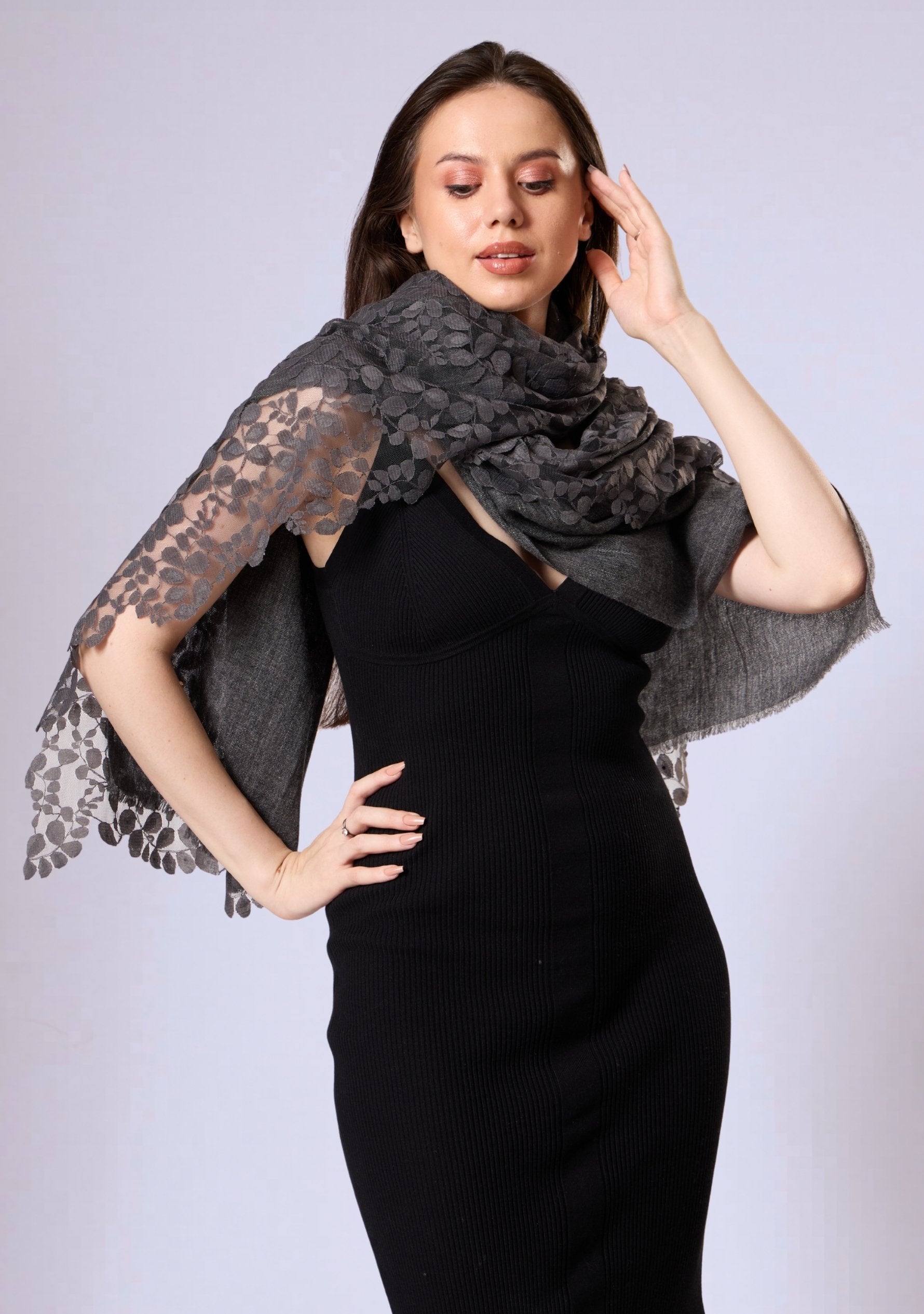Woman wearing a black dress with a gray lace shawl on a light gray background