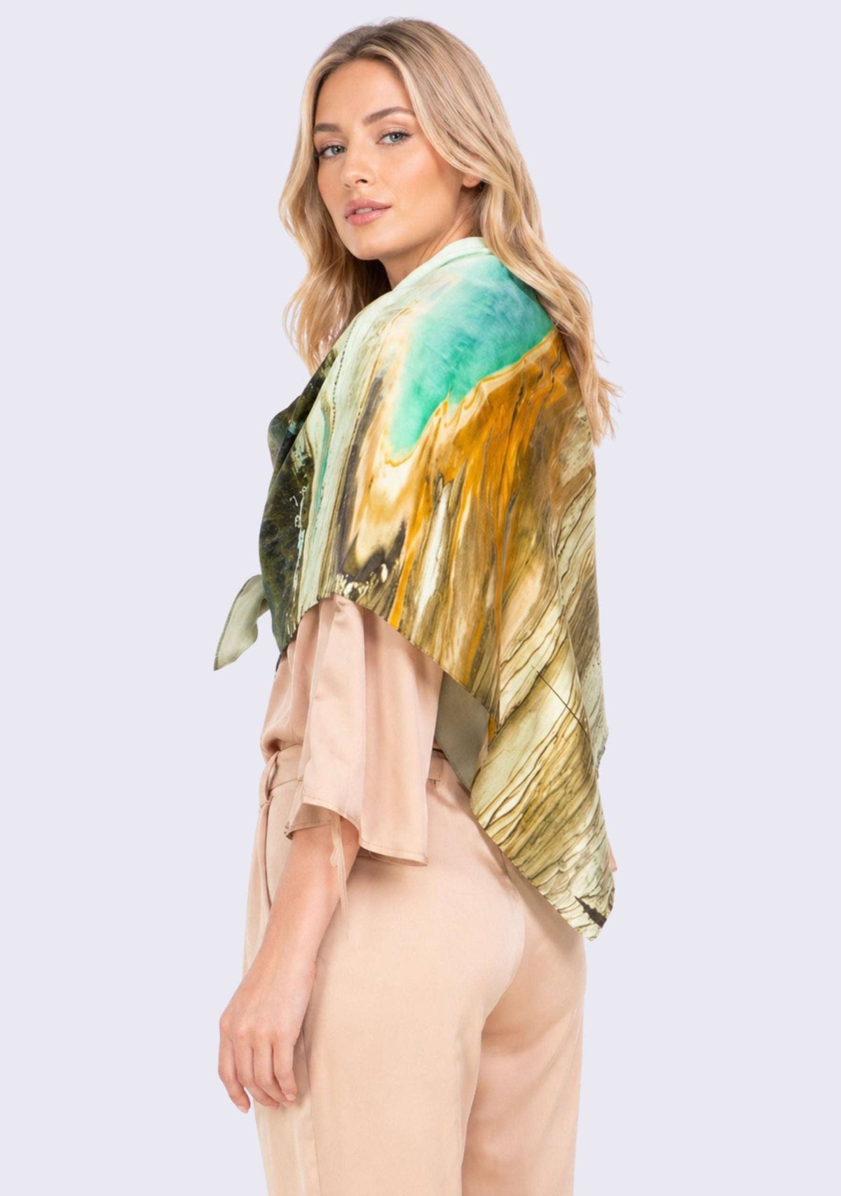 Grand Prismatic Print Silk Square Scarf by Maneesha Ruia draped over the shoulders, showcasing a Yellowstone-inspired landscape print in emerald green, golden amber, ivory, black, and earthy brown on luxurious 100% silk.