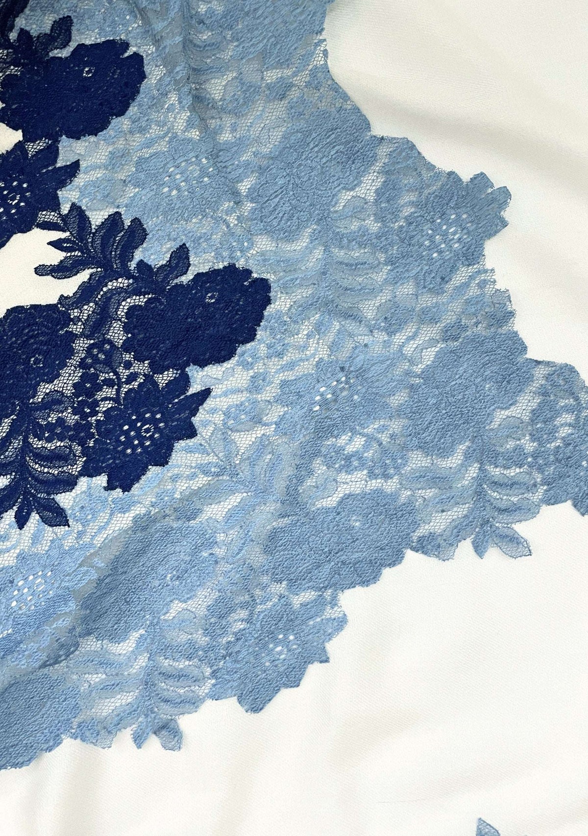 Close-up of a luxury ivory wool and silk scarf featuring handcrafted steel blue and dark denim blue Chantilly floral lace, highlighting the intricate floral lace craftsmanship, rich two-tone detailing, and premium wool-silk fabric.