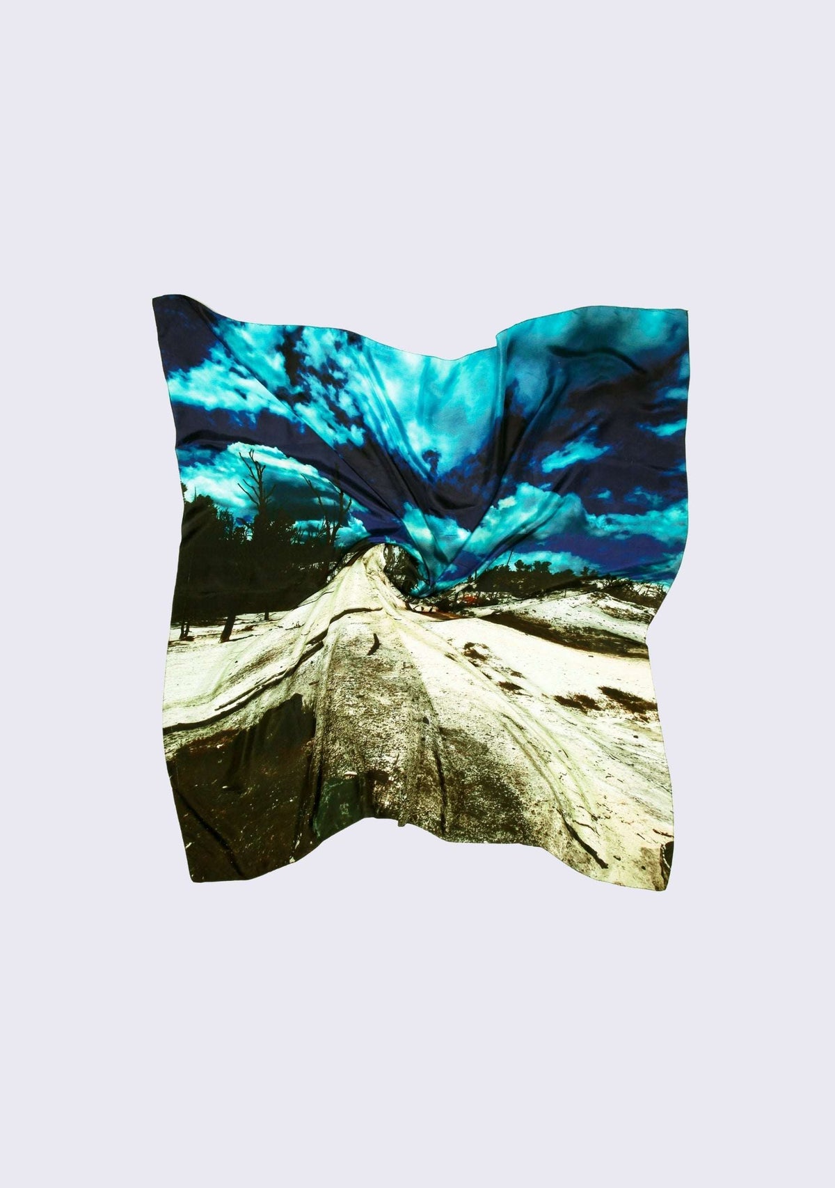 Mammoth Hot Springs Print Silk Square Scarf by Maneesha Ruia featuring a dramatic landscape print with vivid turquoise-blue sky, rugged white geothermal terrain, and deep black accents on luxurious 100% silk.
