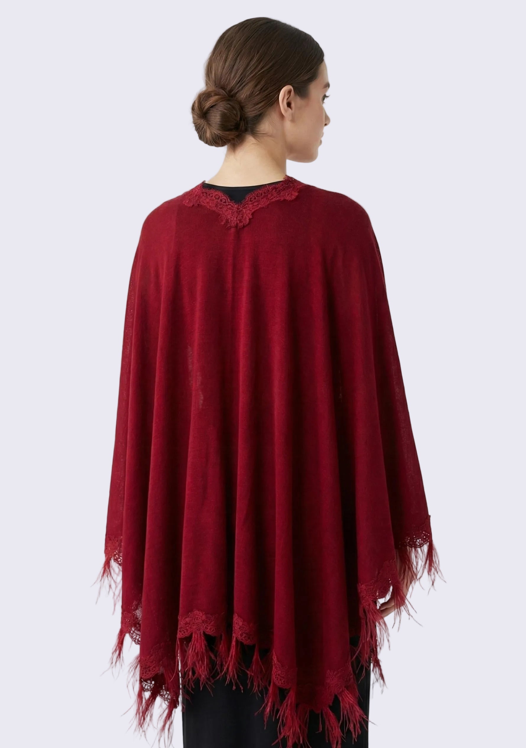 Red poncho with lace trim worn by a person on a white background