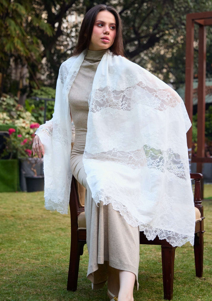 Woman sitting outdoors wearing a Maneesha Ruia Ivory linen and modal scarf with ivory lace panels over a beige outfit.