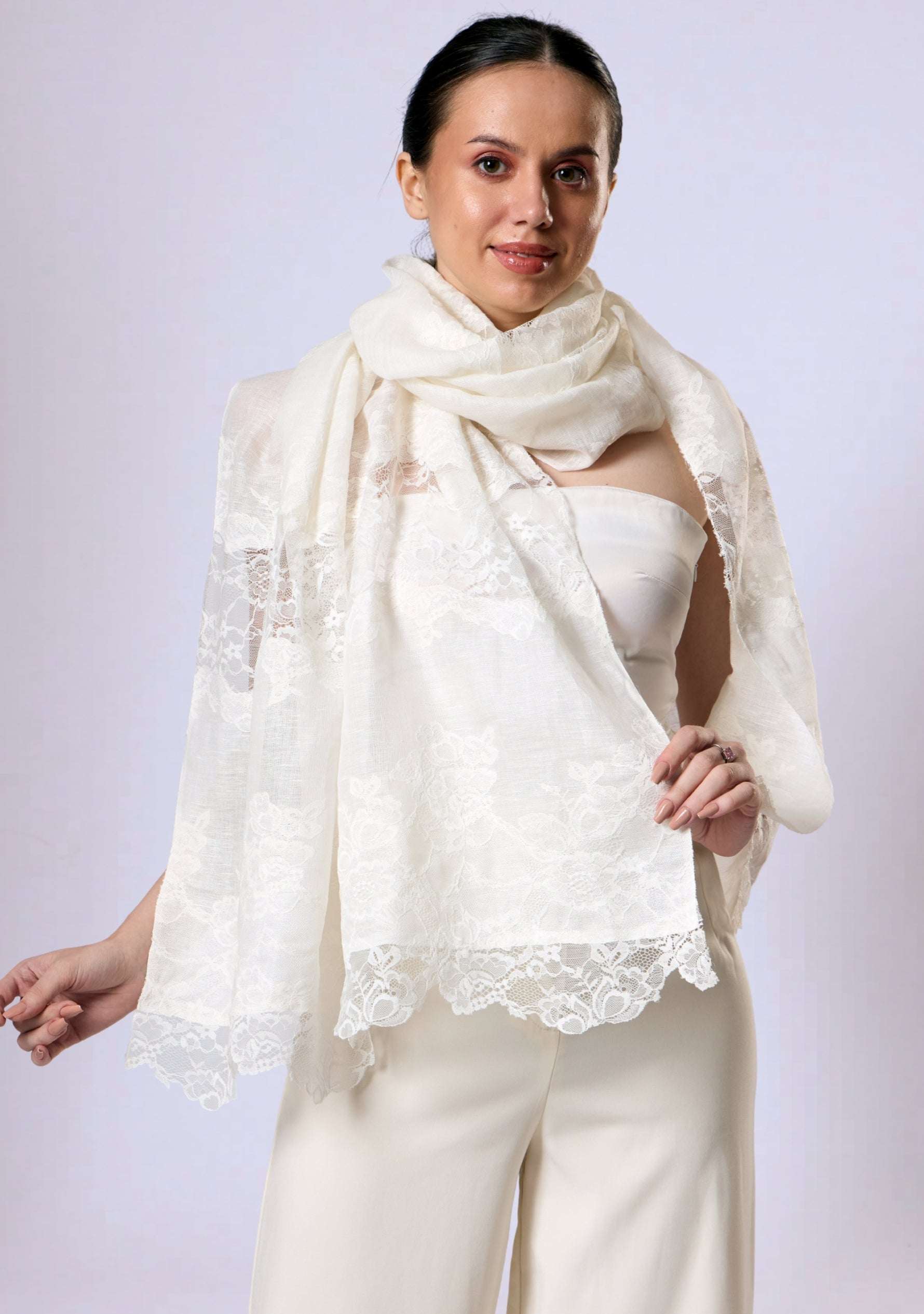 Woman sitting outdoors wearing a Maneesha Ruia Ivory linen and modal scarf with ivory lace panels over a ivory outfit.