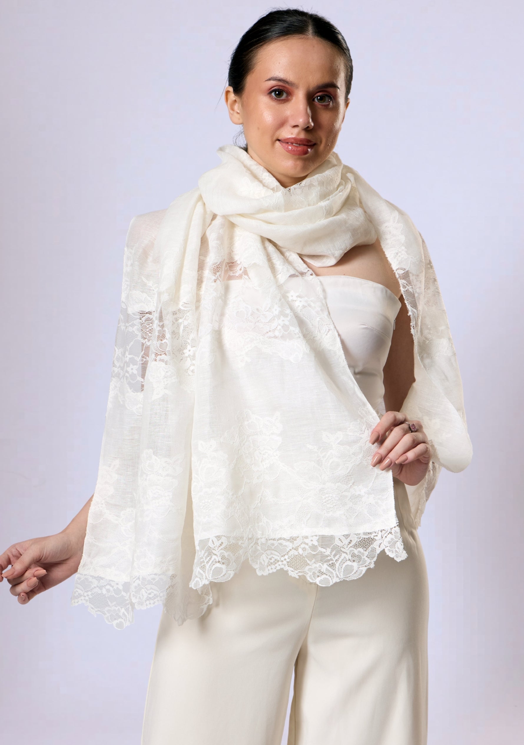 Woman sitting outdoors wearing a Maneesha Ruia Ivory linen and modal scarf with ivory lace panels over a ivory outfit.
