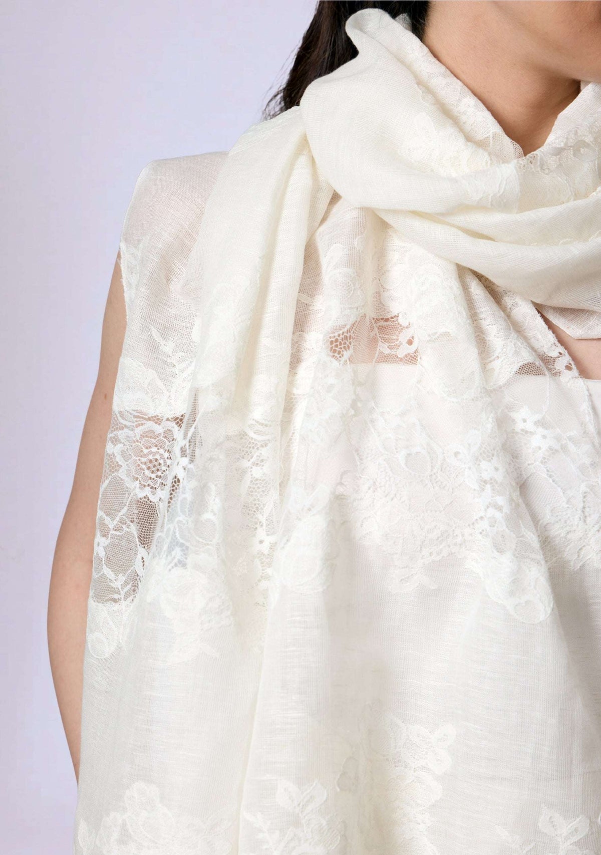 Woman sitting outdoors wearing a Maneesha Ruia Ivory linen and modal scarf with ivory lace panels over an ivory outfit.