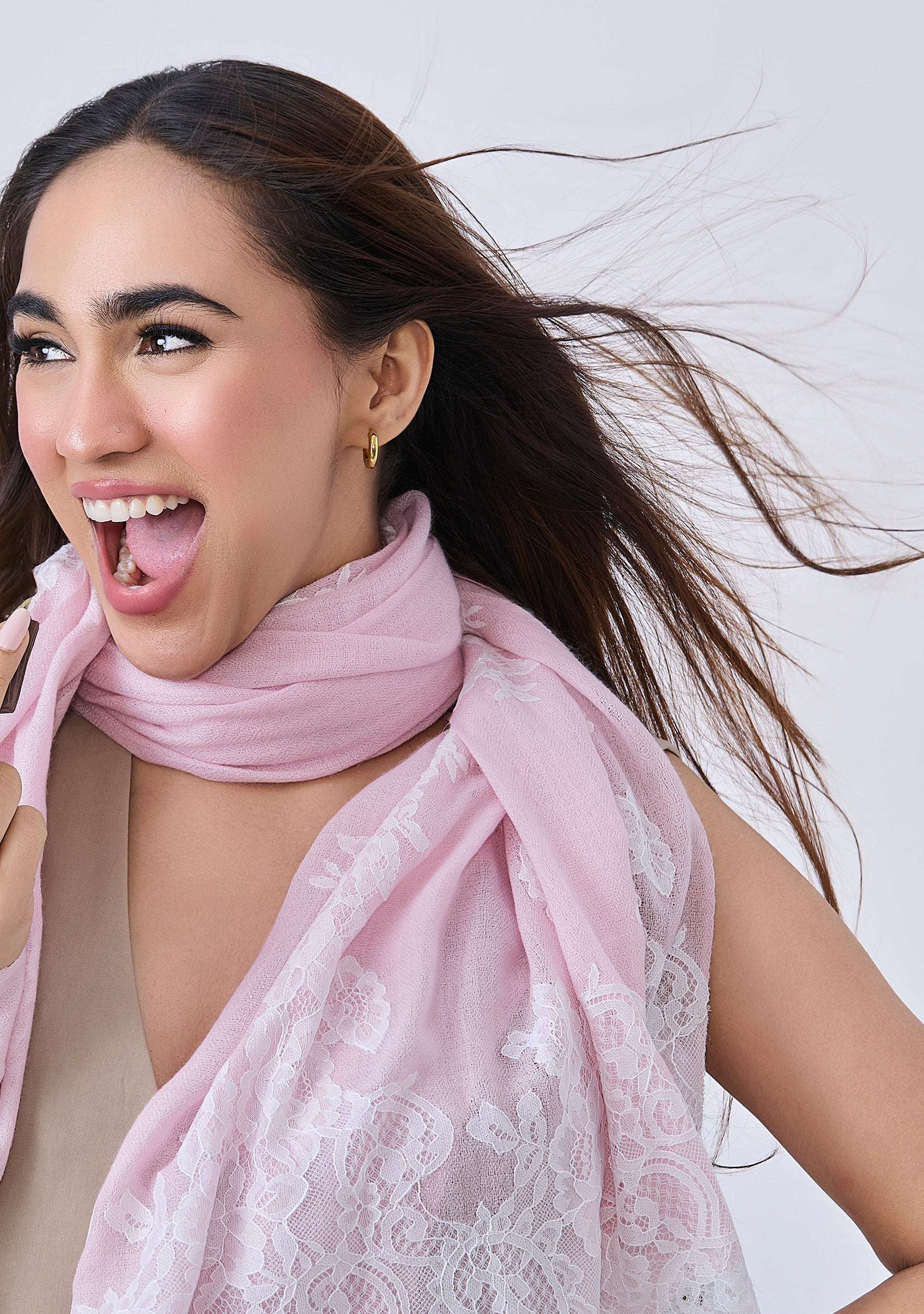 A woman wearing a Maneesha Ruia Baby Pink Cashmere Scarf — delicate white filigree lace on luxuriously soft cashmere details around her neck.