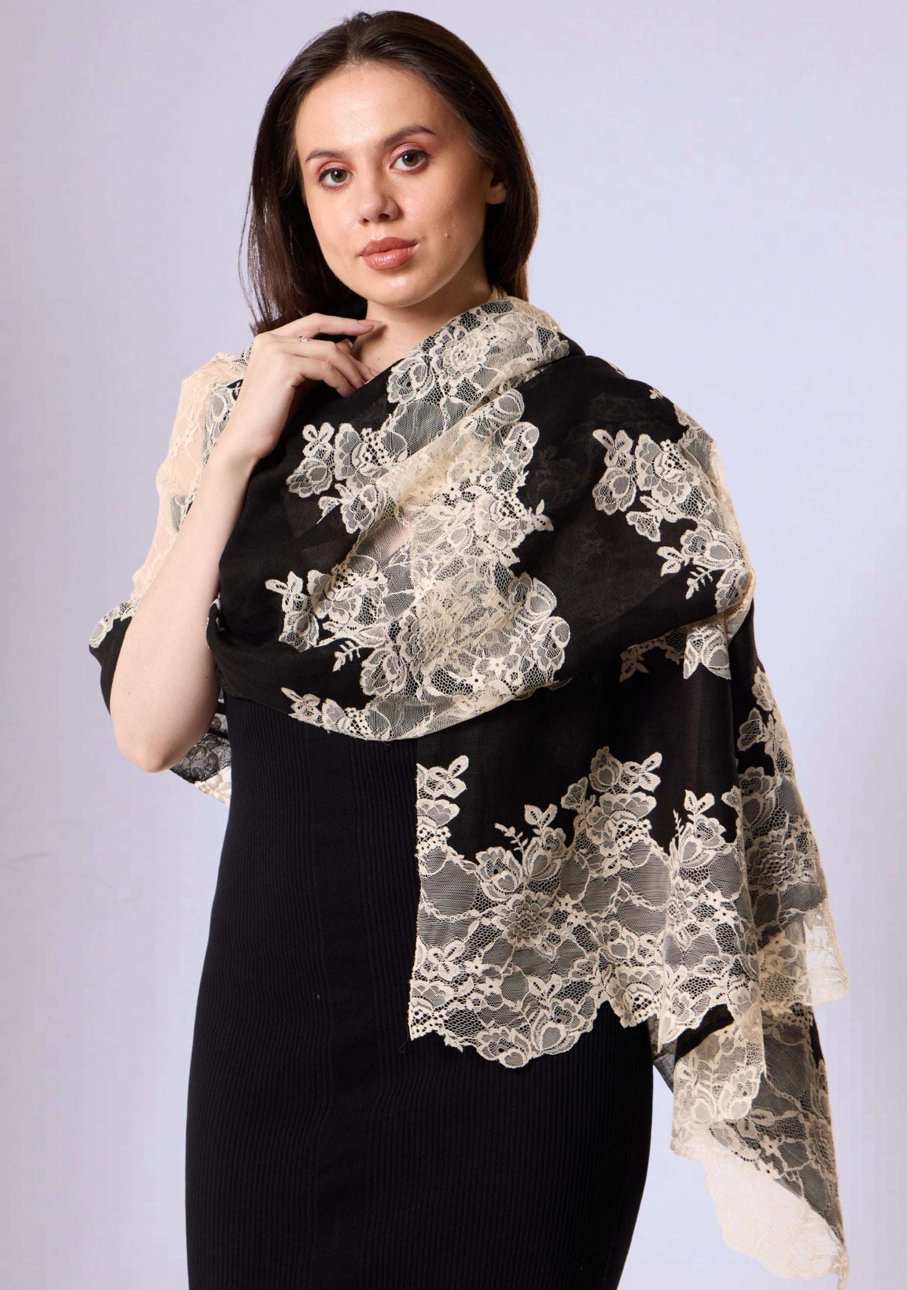 Woman wearing a black dress with a white lace shawl on a light gray background