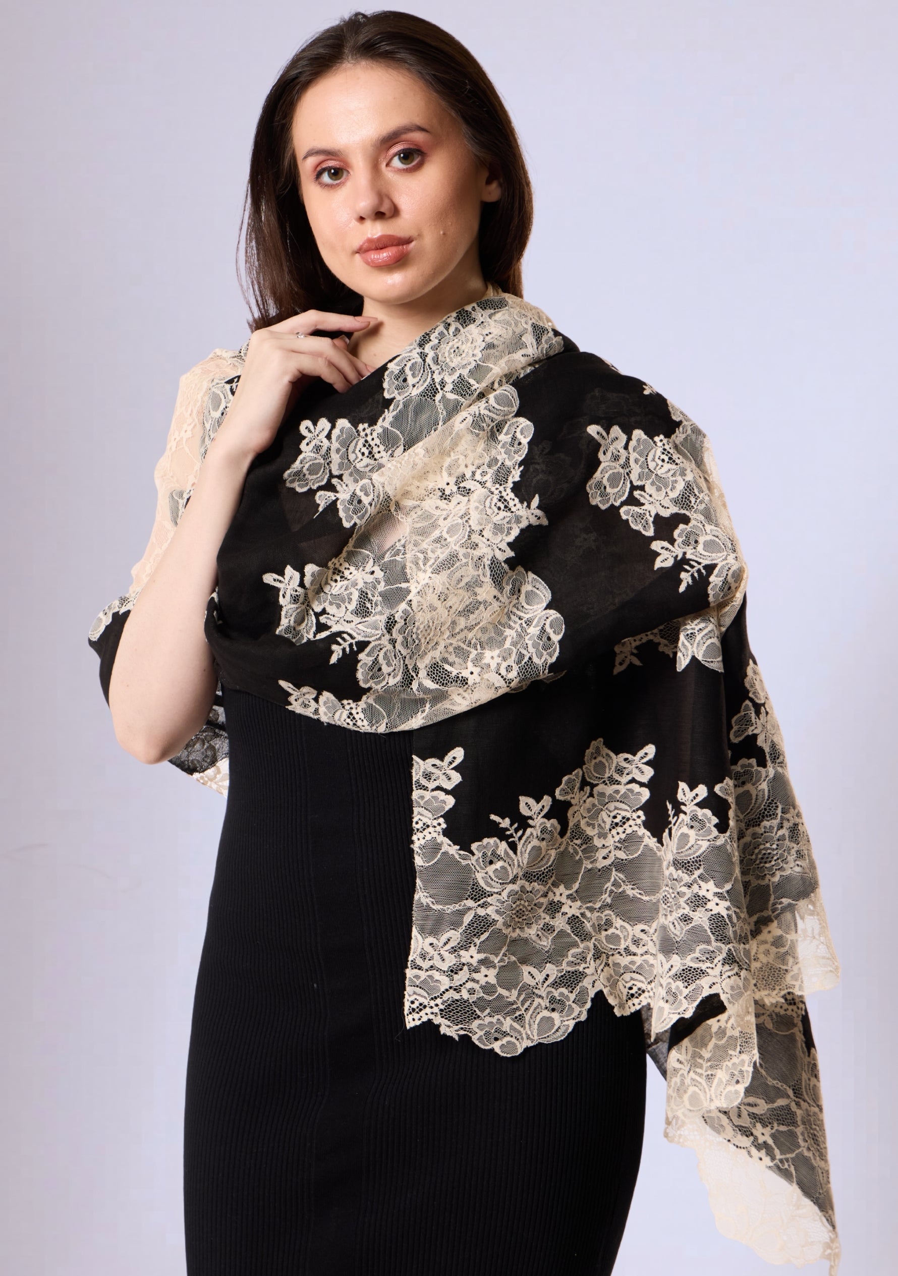 Woman wearing a black dress with a white lace shawl on a light gray background