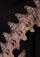 Close-up of intricate lace detailing on a black wool cape against a dark background