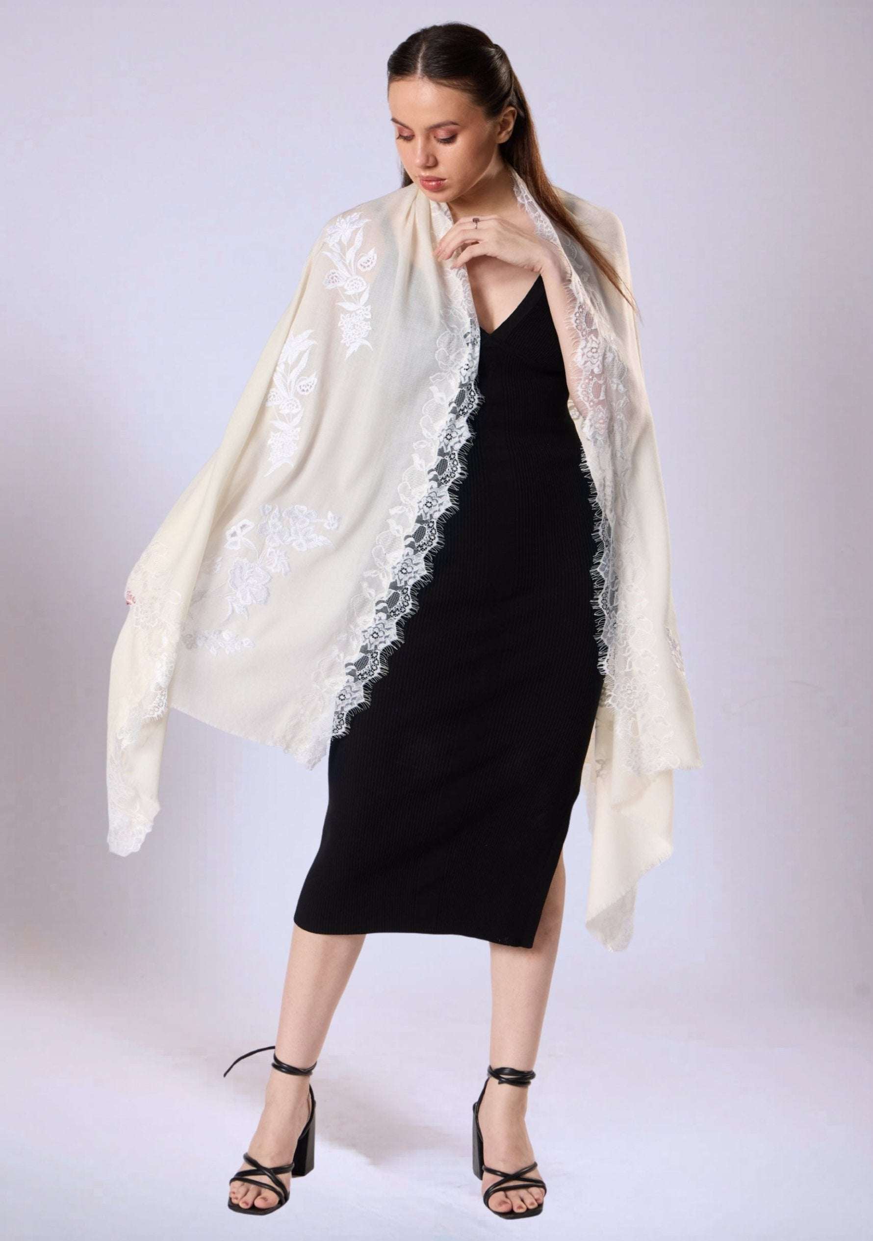 Woman wearing a black dress with a white lace shawl on a white background