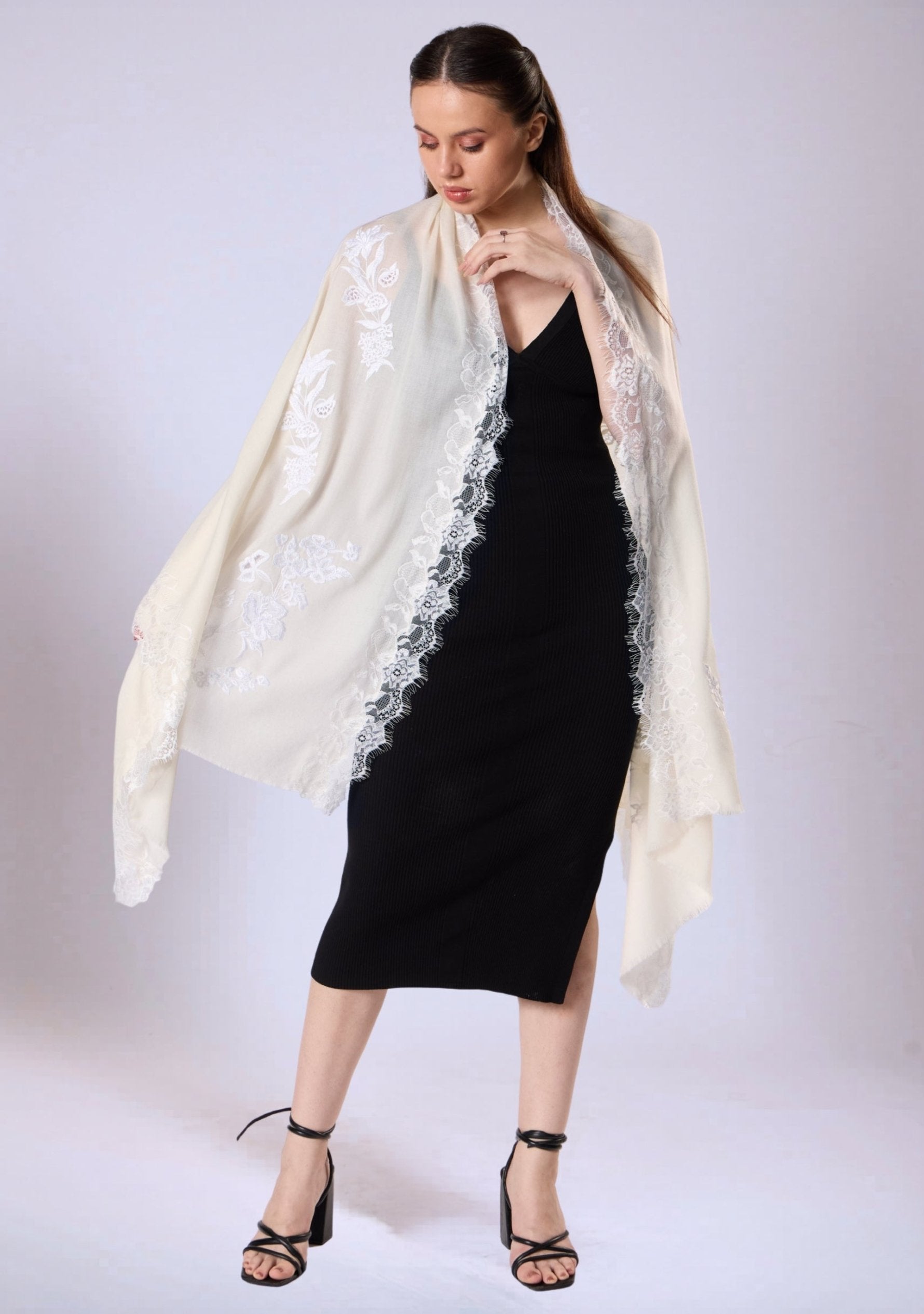 Woman wearing a black dress with a white lace shawl on a white background
