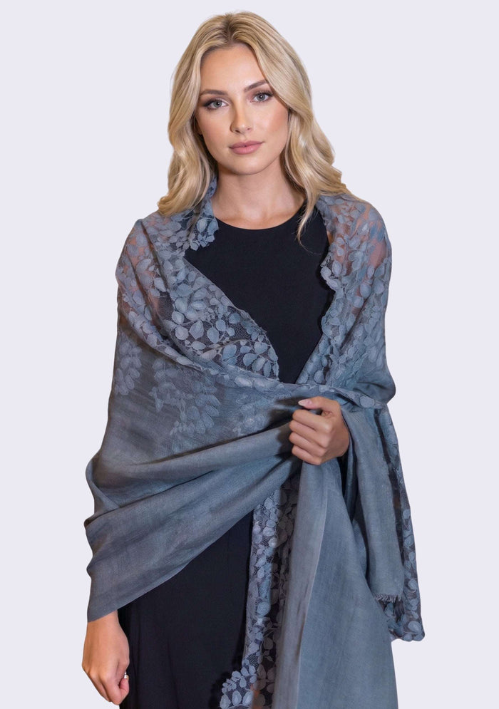 Woman wearing a gray lace shawl over a black outfit on a white background