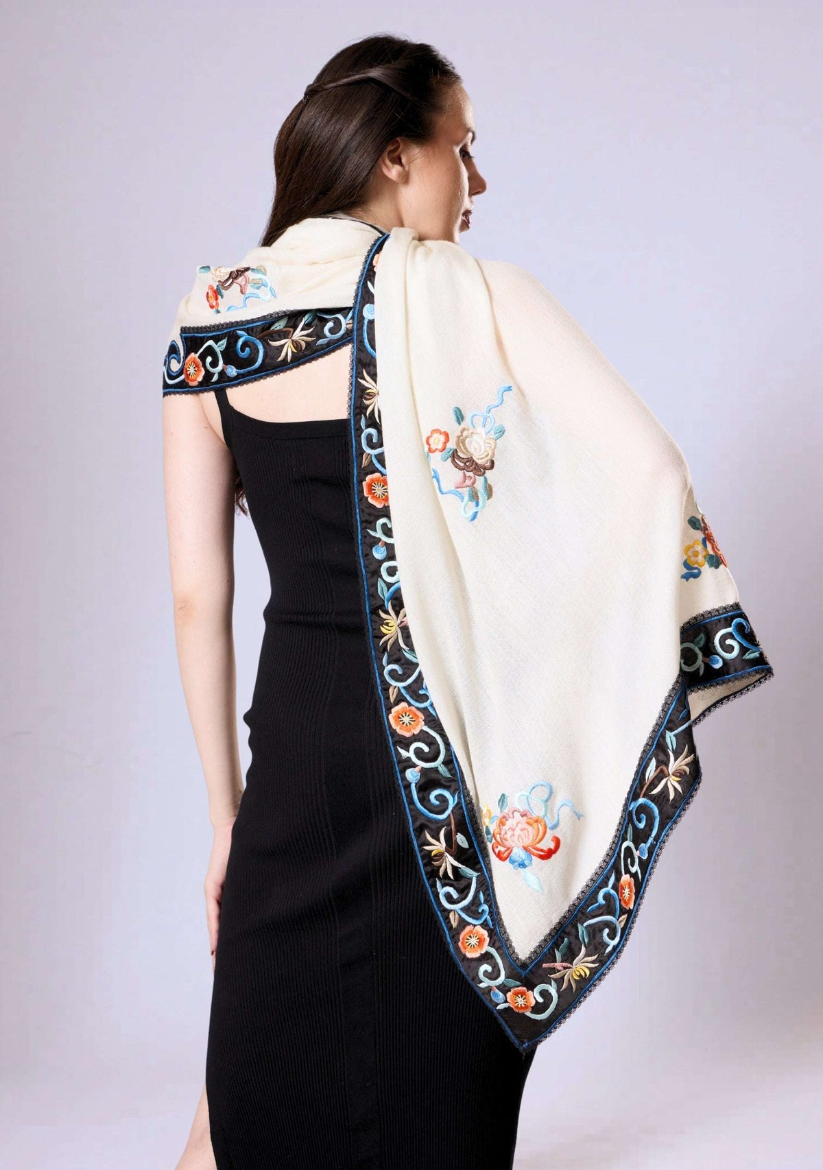 Woman wearing a black dress with an embroidered white shawl draped over her shoulders.